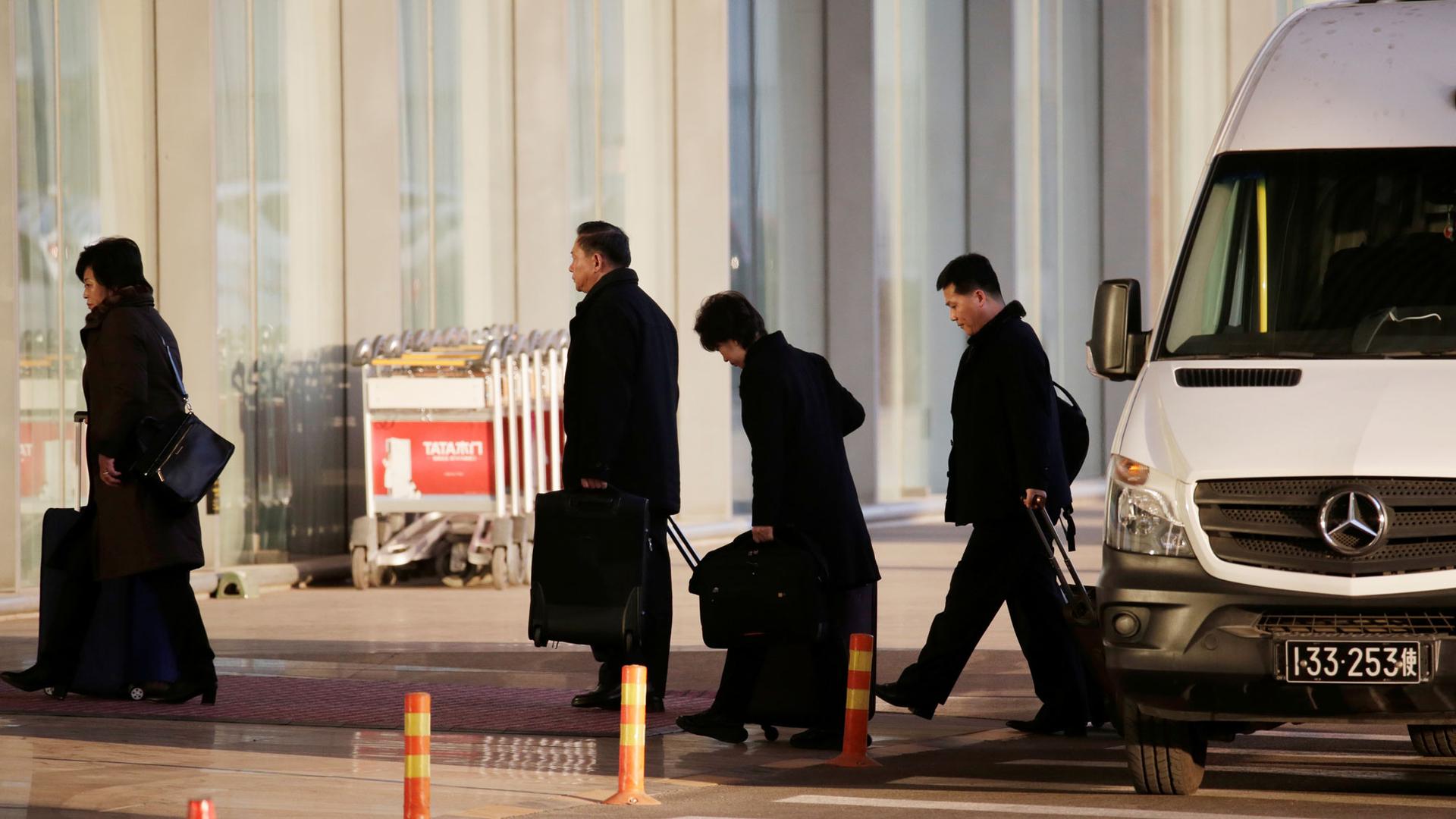 North Korean officials are shown walking from a white van with luggage at the international airport in Beijing, China.