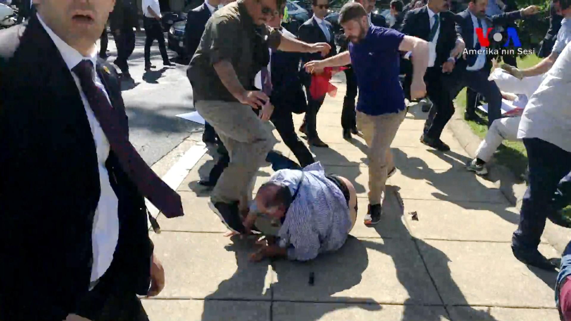 two men kick a protester on the ground 