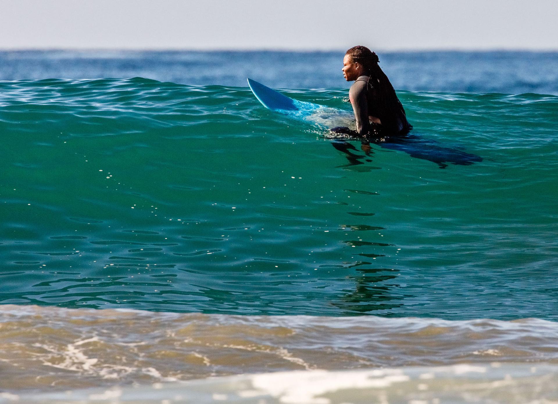 A woman sits on her board waiting for a wave