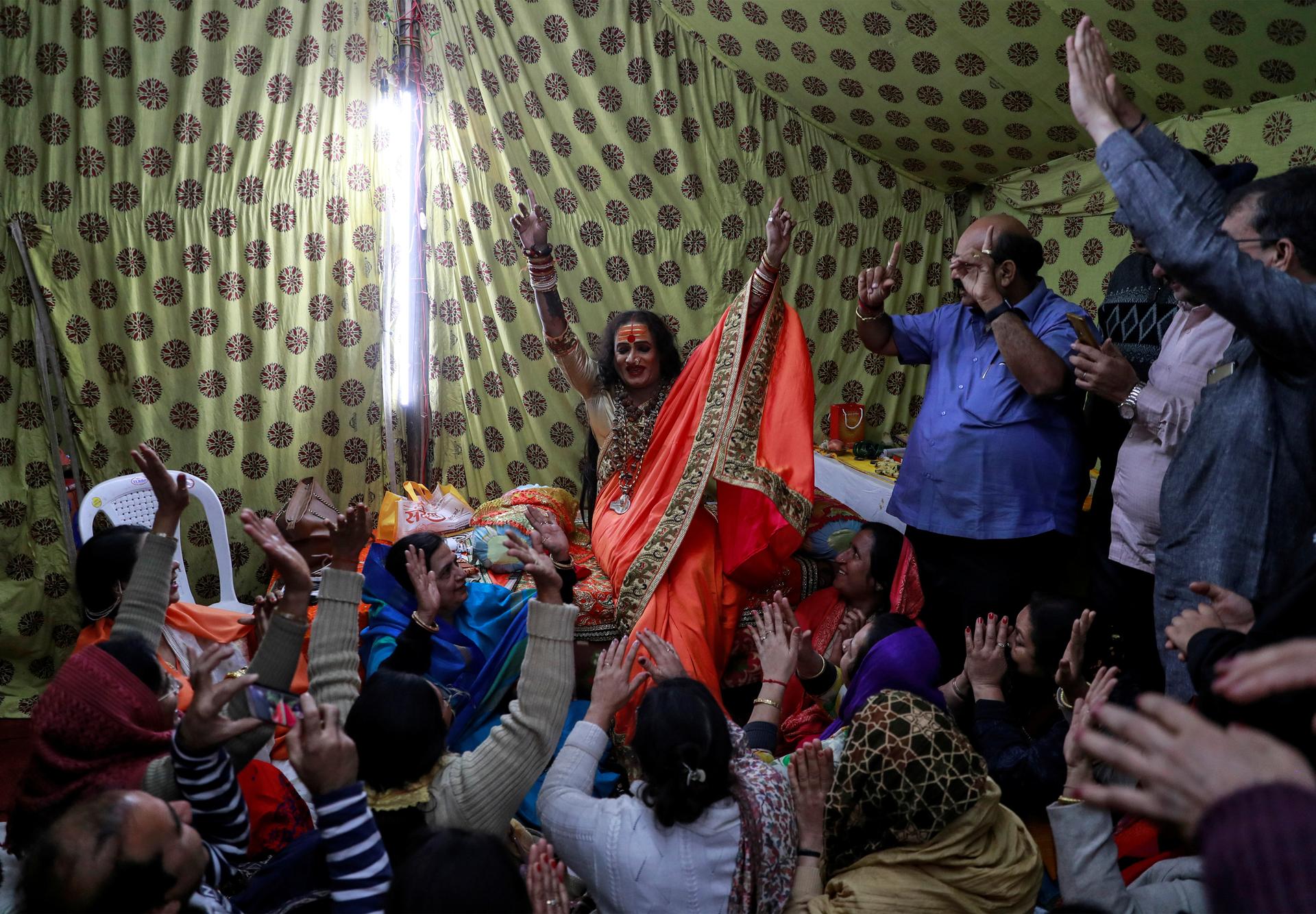 A transgender Indian woman in front of a crowd with hands raised