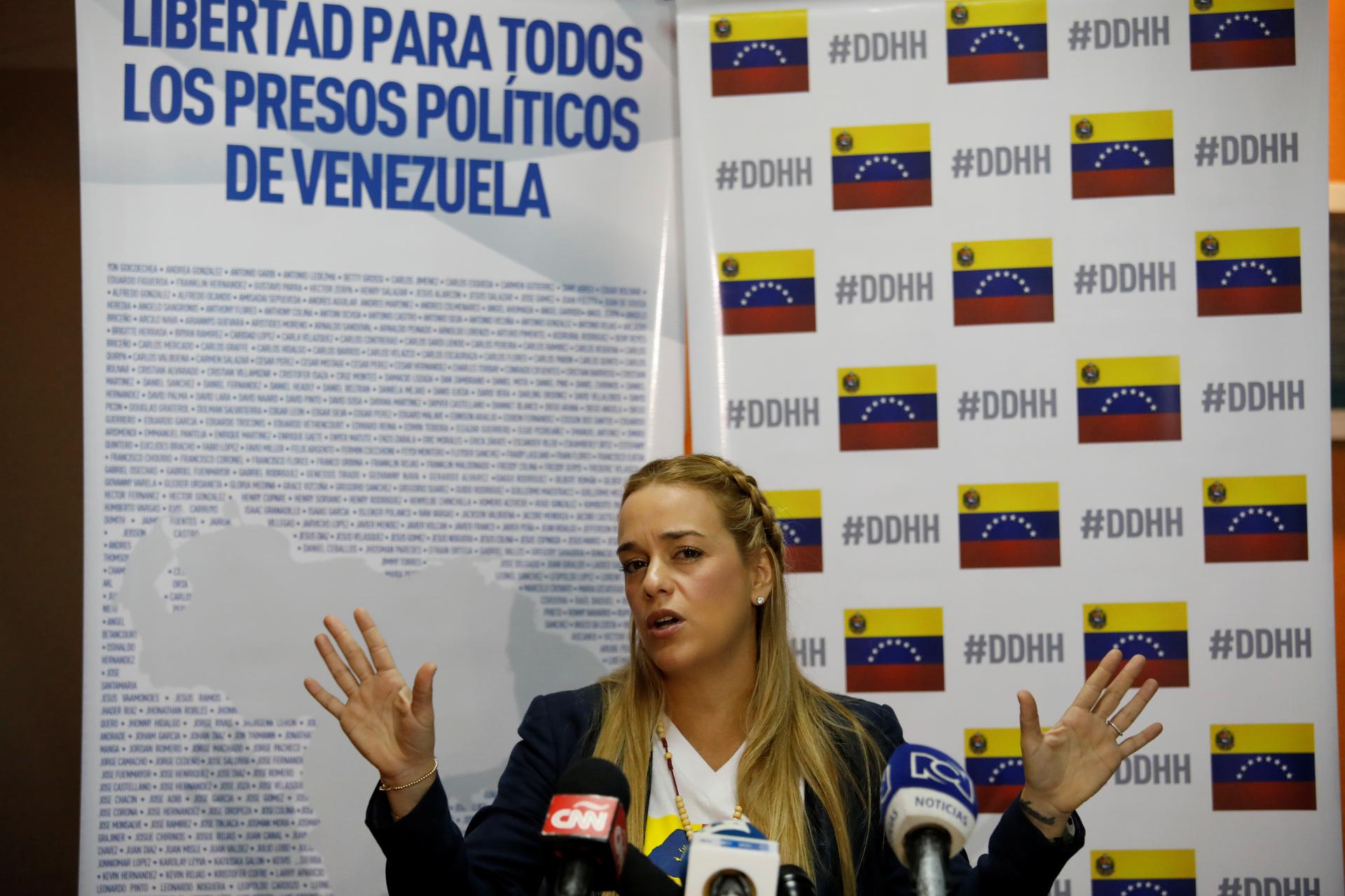 A blonde Lilian Tintori, speaks during a meeting with a banner in the background that reads: "Freedom for all the political prisoners in Venezuela." 