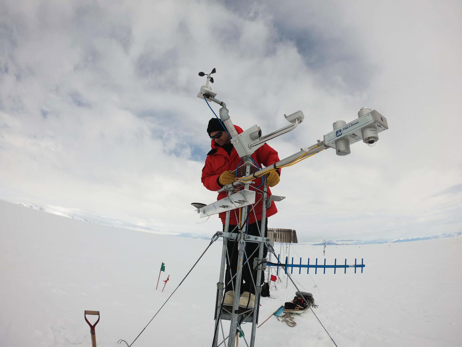 a man in a red coat stands on top of a large research instrument