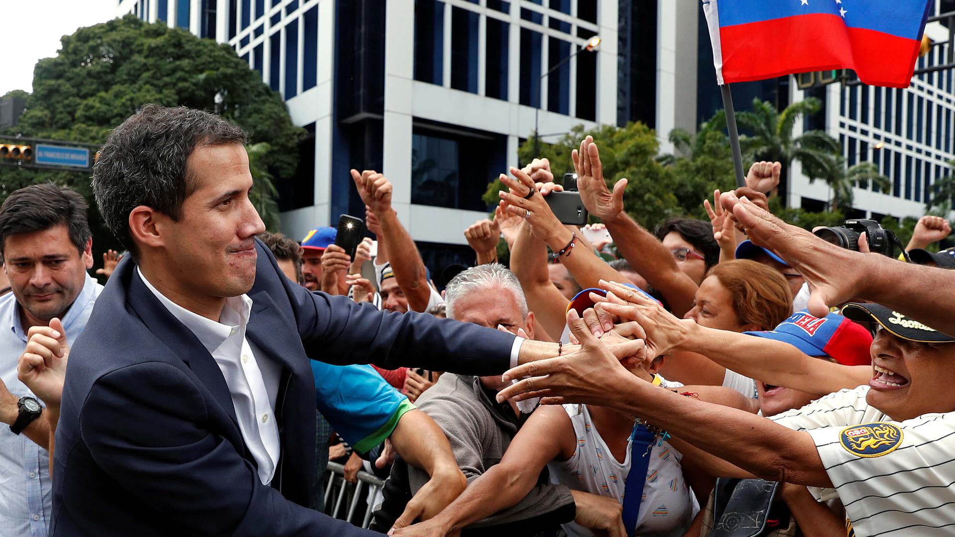 Politician shakes many hands at a rally. 