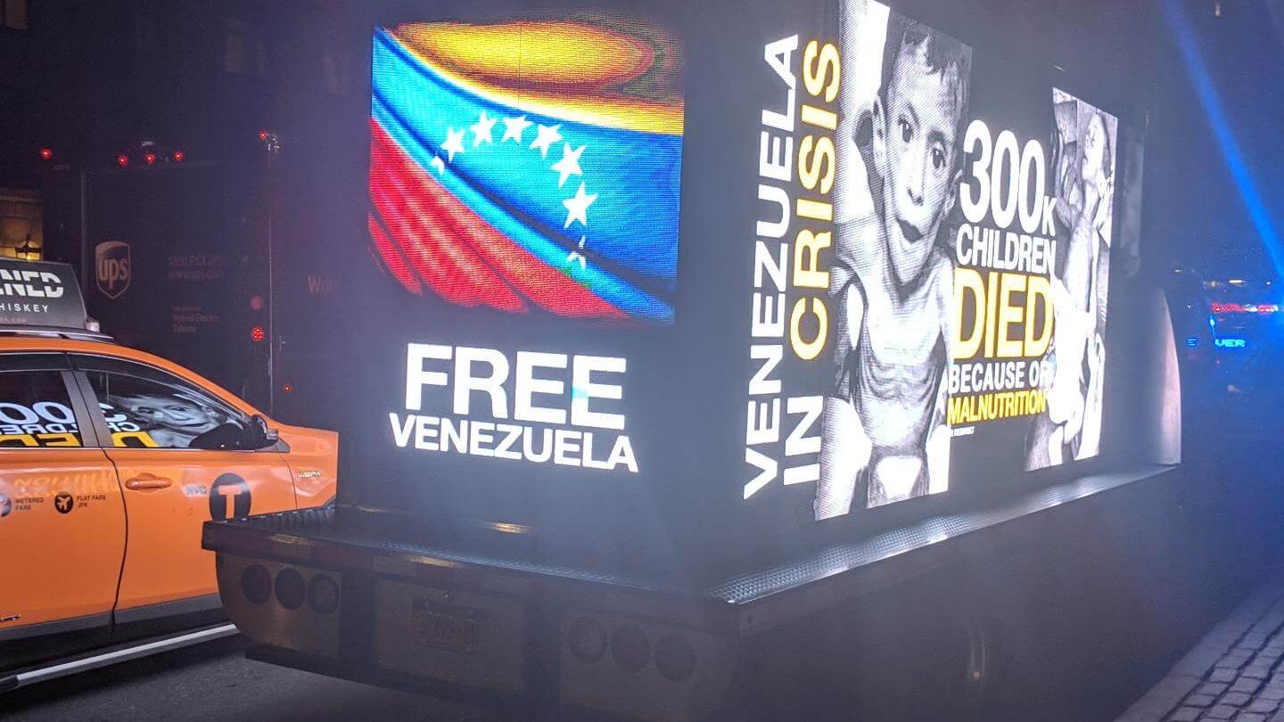 A glowing billboard on a mobile truck says Free Venezuela. 