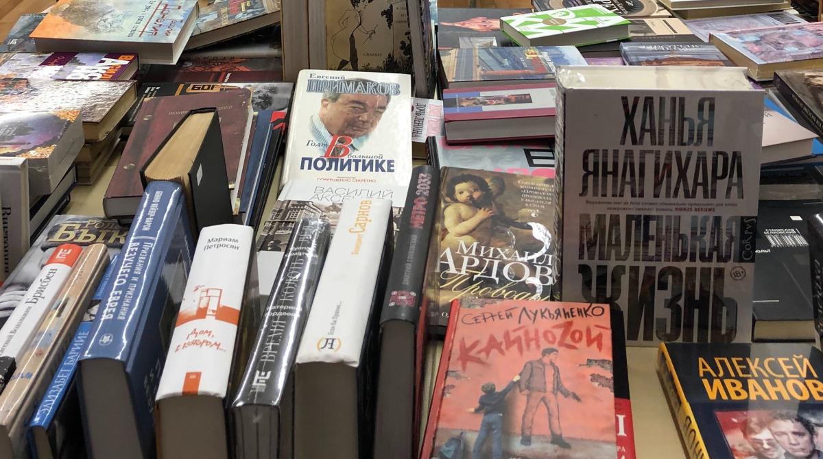 Dozens of books in Russian are on display on a table inside a bookstore.
