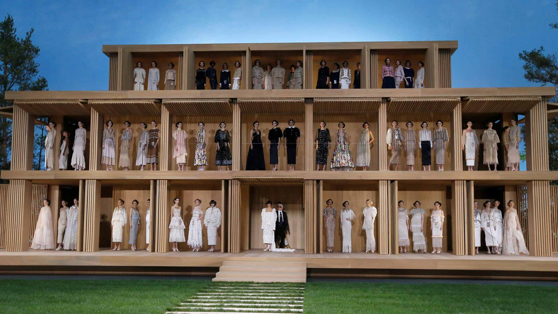 Models are standing on three levels of a wooden house as part of a spring fashion show.