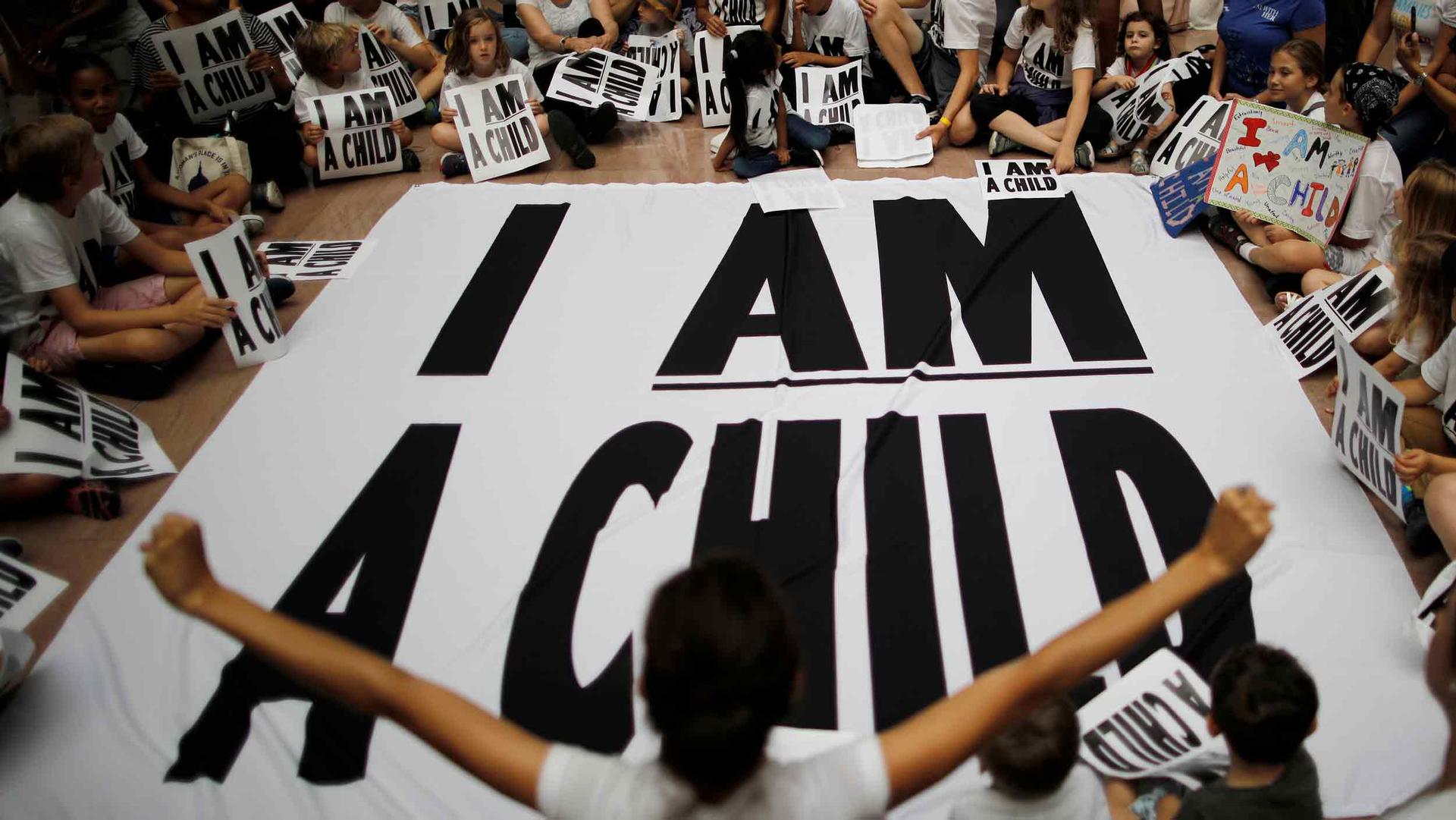 Young children hold signs that say 