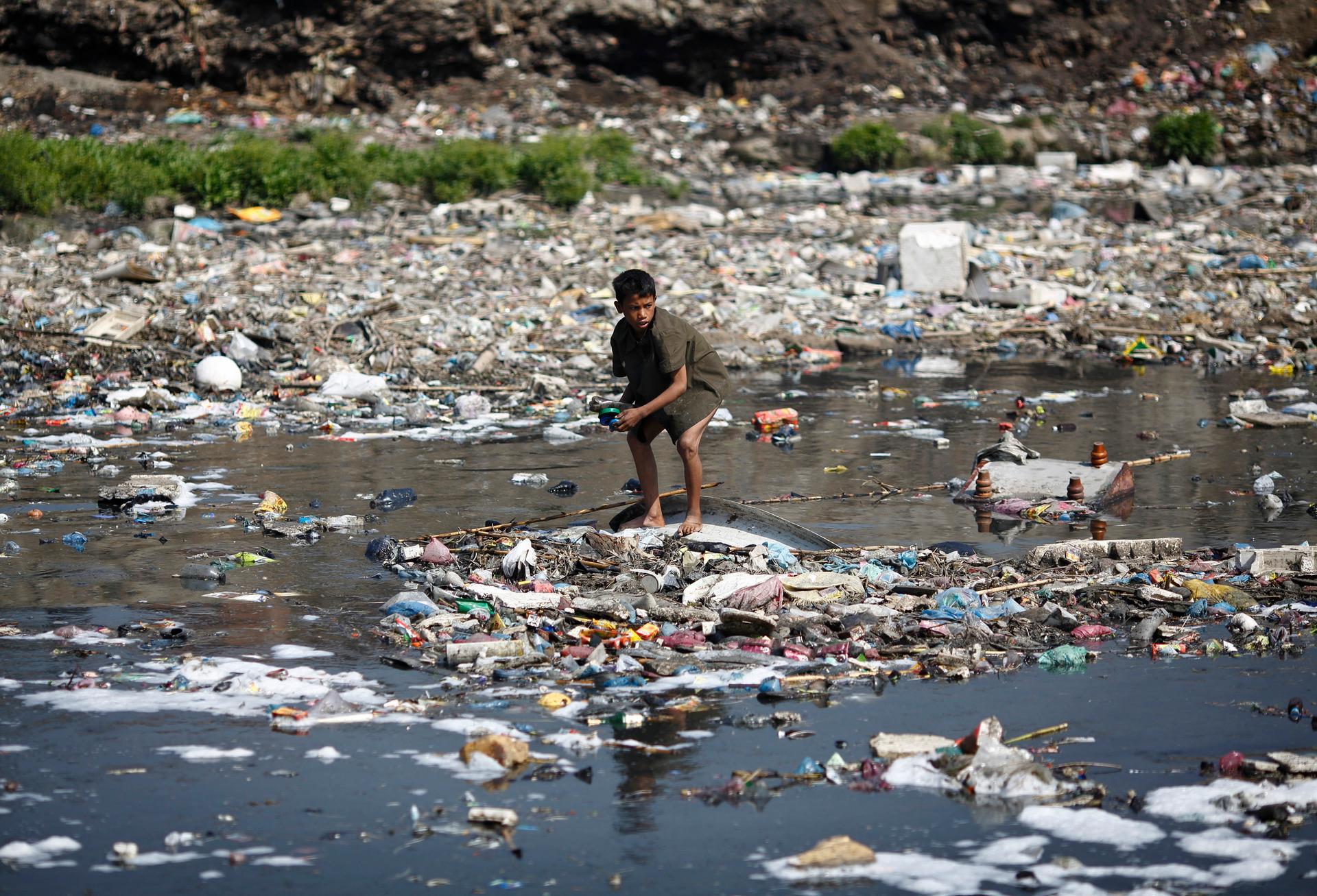 A boy crouches on an island of plastic. 