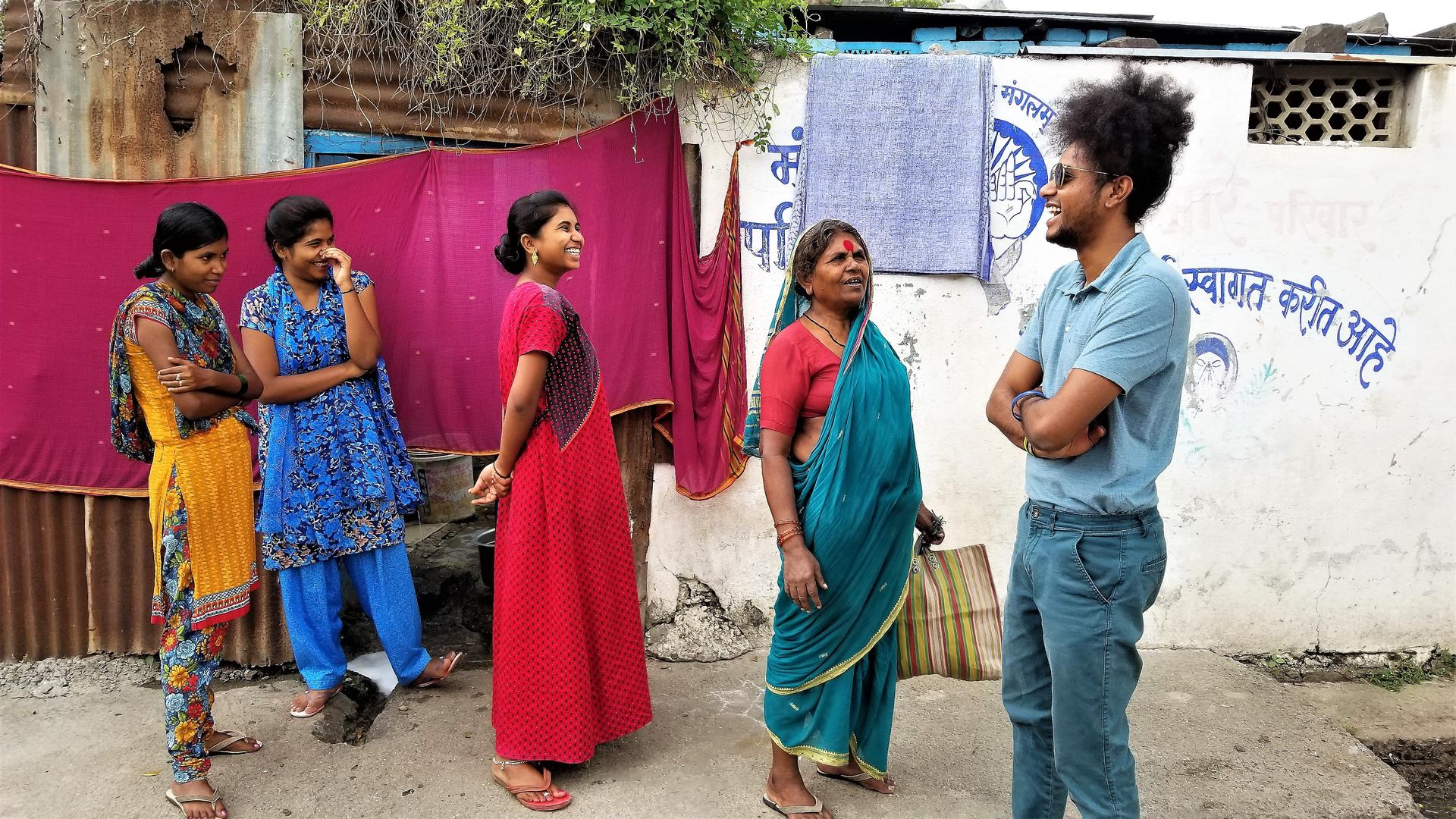Several women in saris and a man laugh