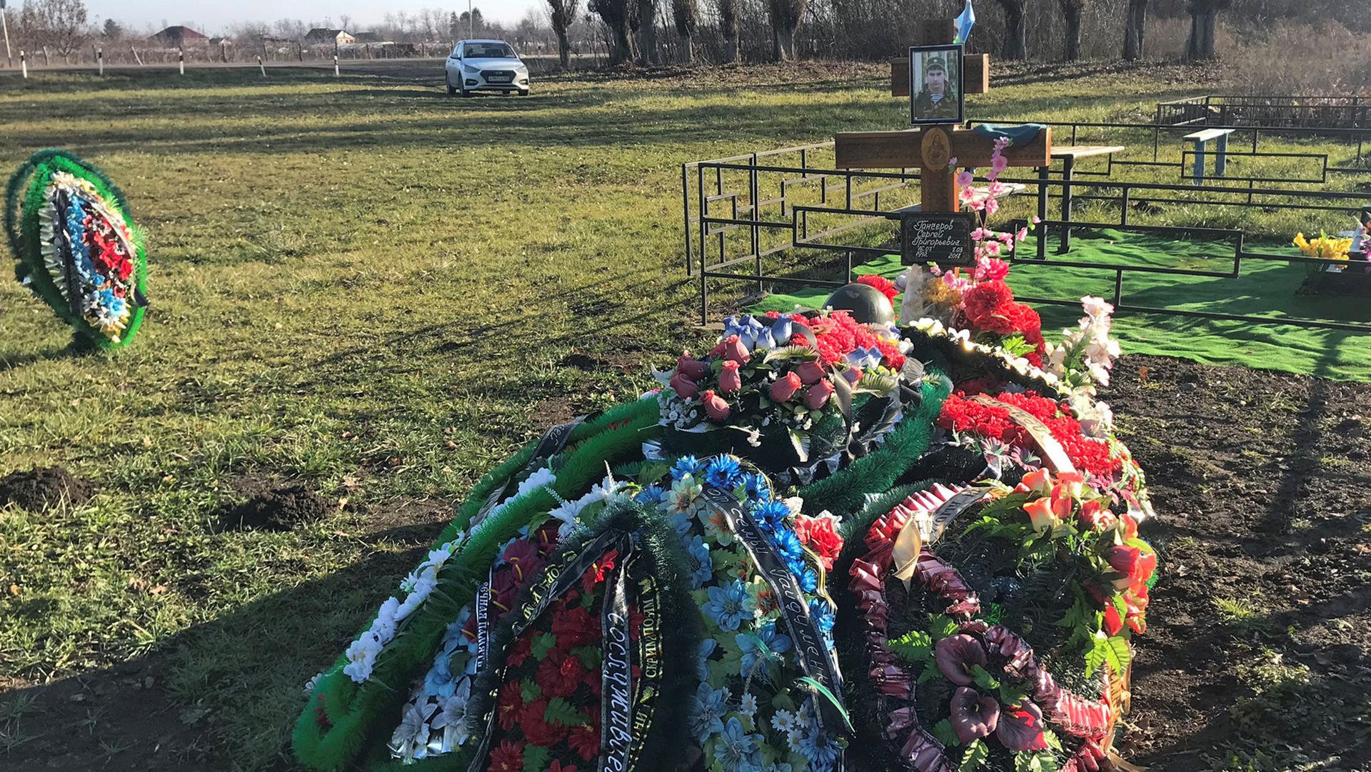 The grave of Russian private military contractor Sergei Gancherov is shown adorned with flowers and his photograph on a cross.