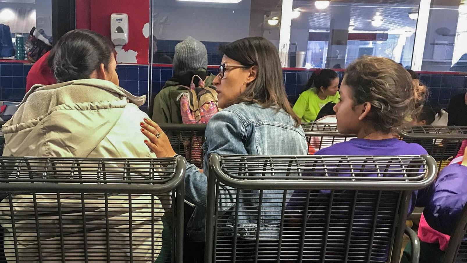 Alicia Cruz, in the center of the photograph, is shown wearing a jean jacket and putting her left hand on the shoulder of the woman next to her.
