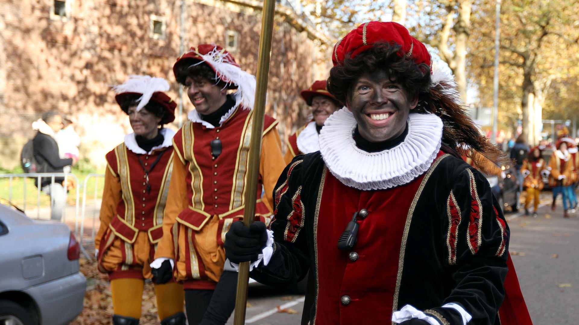 Parade participants in Amsterdam, Netherlands, are shown in jester attire and in blackface.