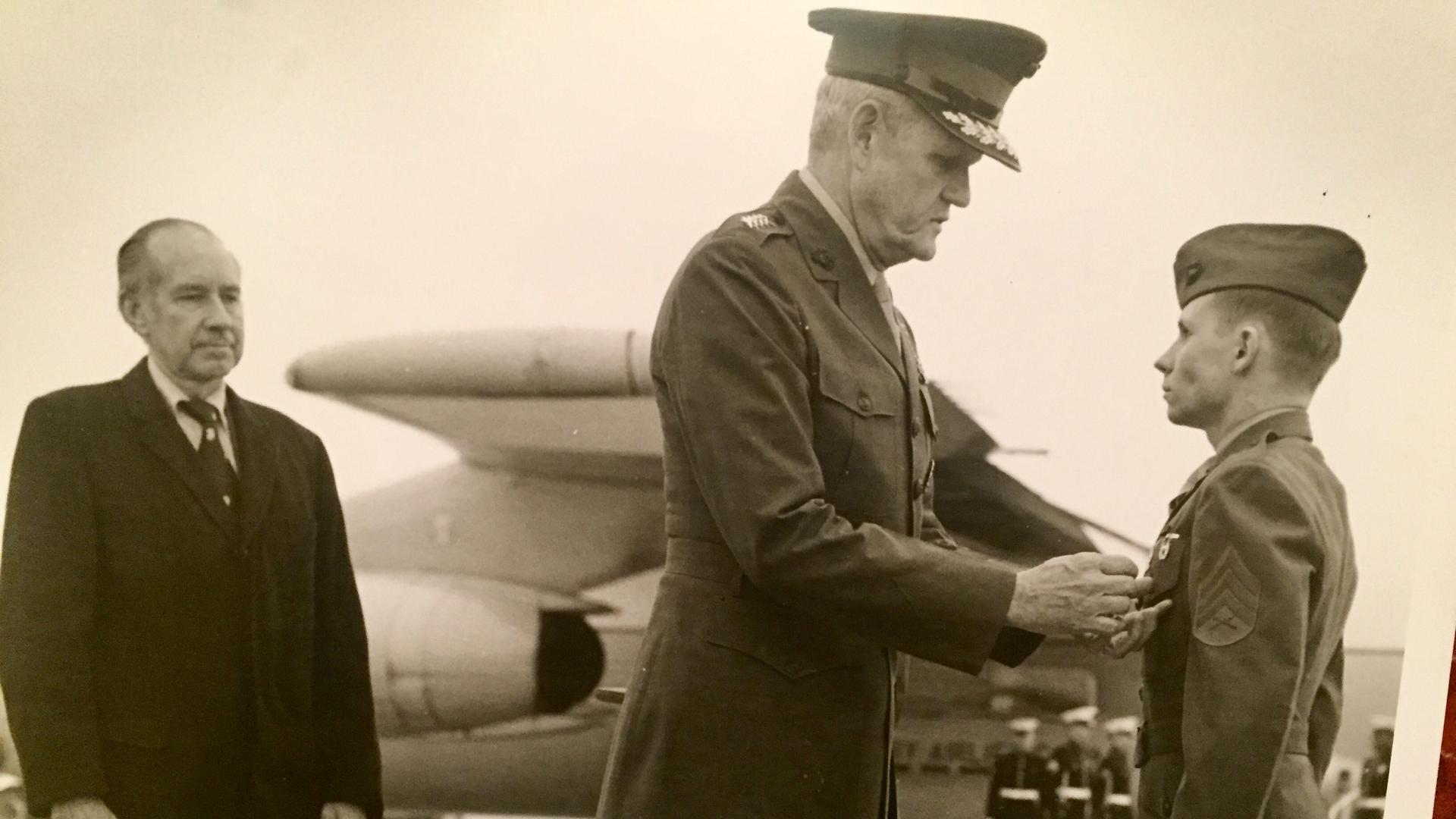 Ken Kraus receives a medal in front of an airplane 