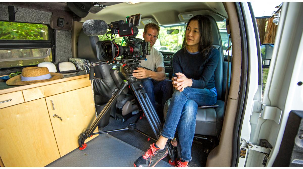 Chai Vasarhelyi seats inside a van with a cameraman and his camera.