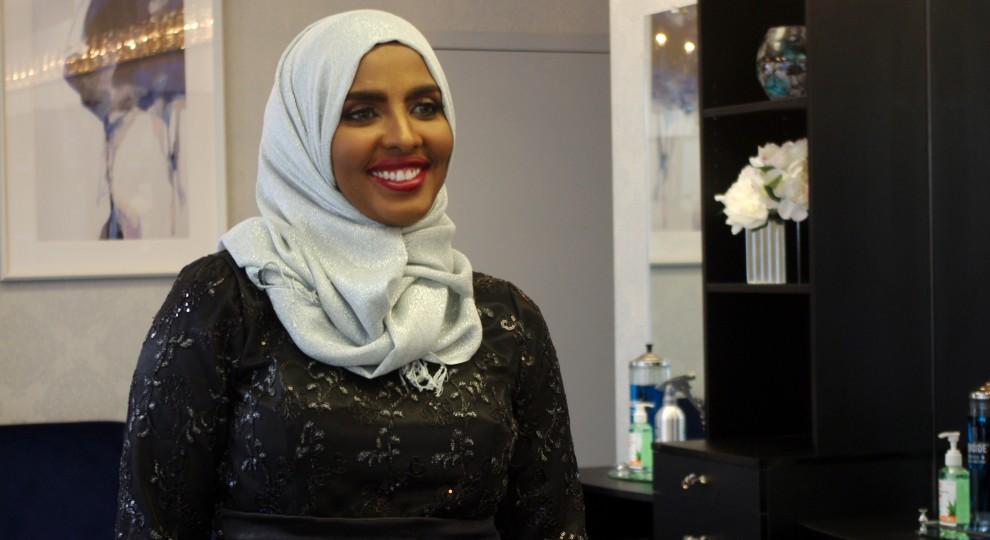 Shamso Ahmed smiles with red lipstick and a white hijab