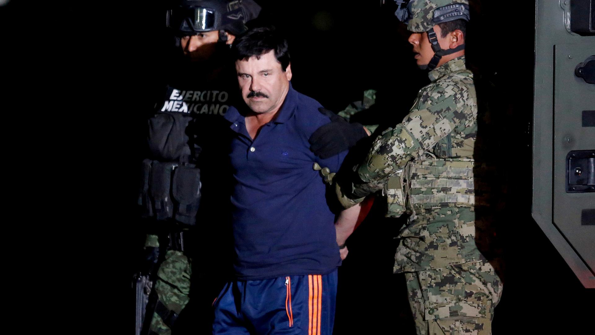 "El Chapo" in blue uniform stands near police.