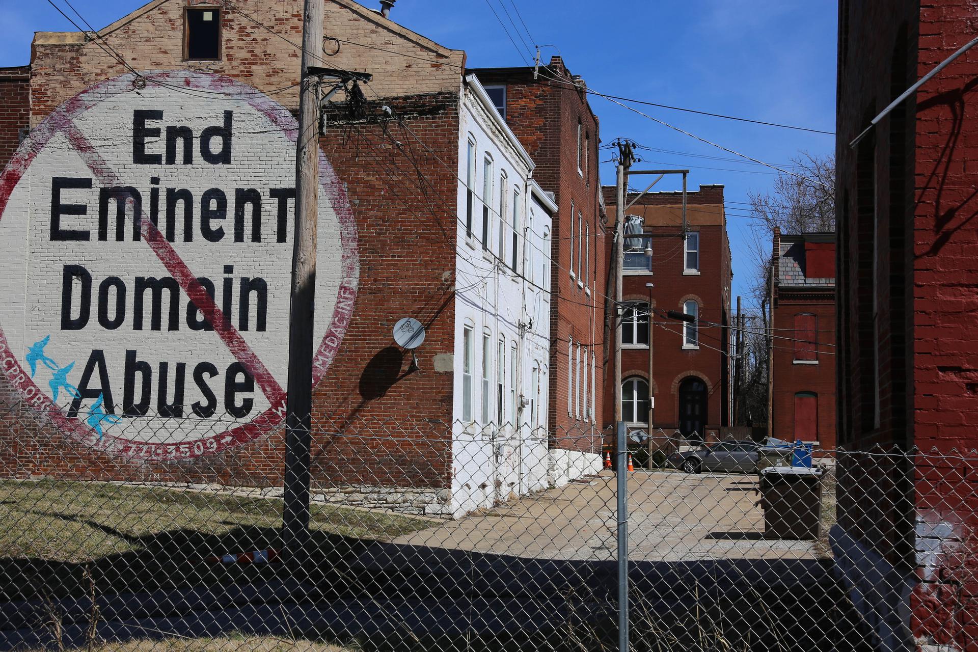 A brick building with hand-painted sign: End Eminent Domain Abuse