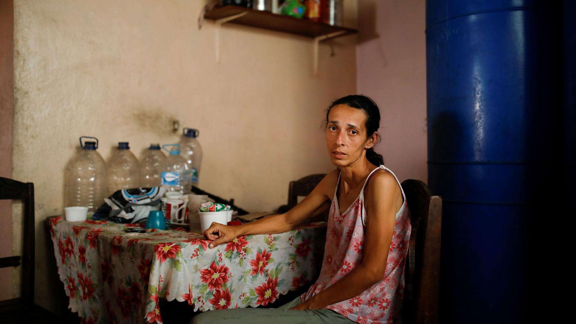 A skinny and malnourished woman poses for a picture while sitting at a table at her home in Caracas, Venezuela. 