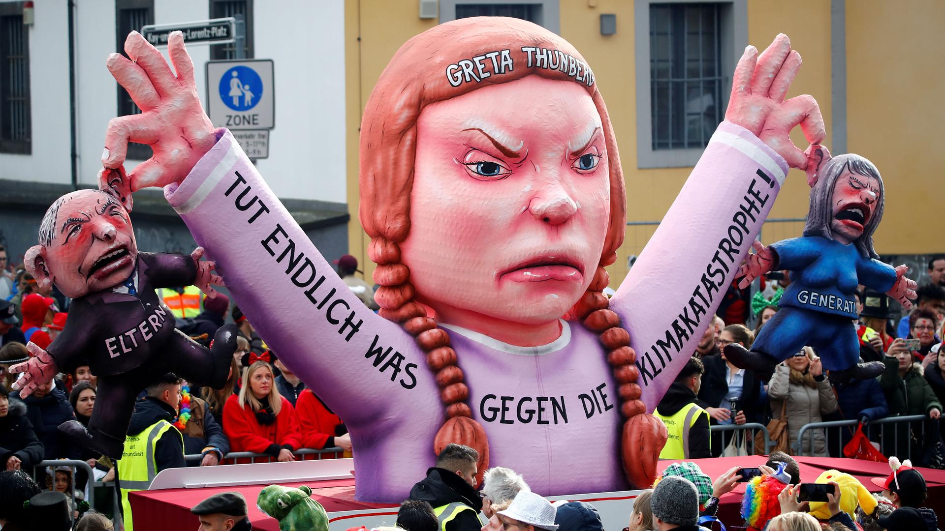 A parade float in the image of Greta Thunberg holds two politicians by the ears