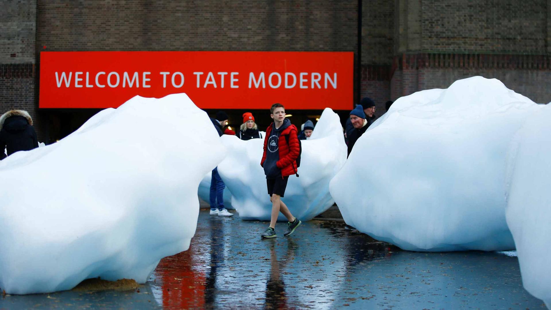 A person stolls between large pieces of ice in front of the Tate Modern in London