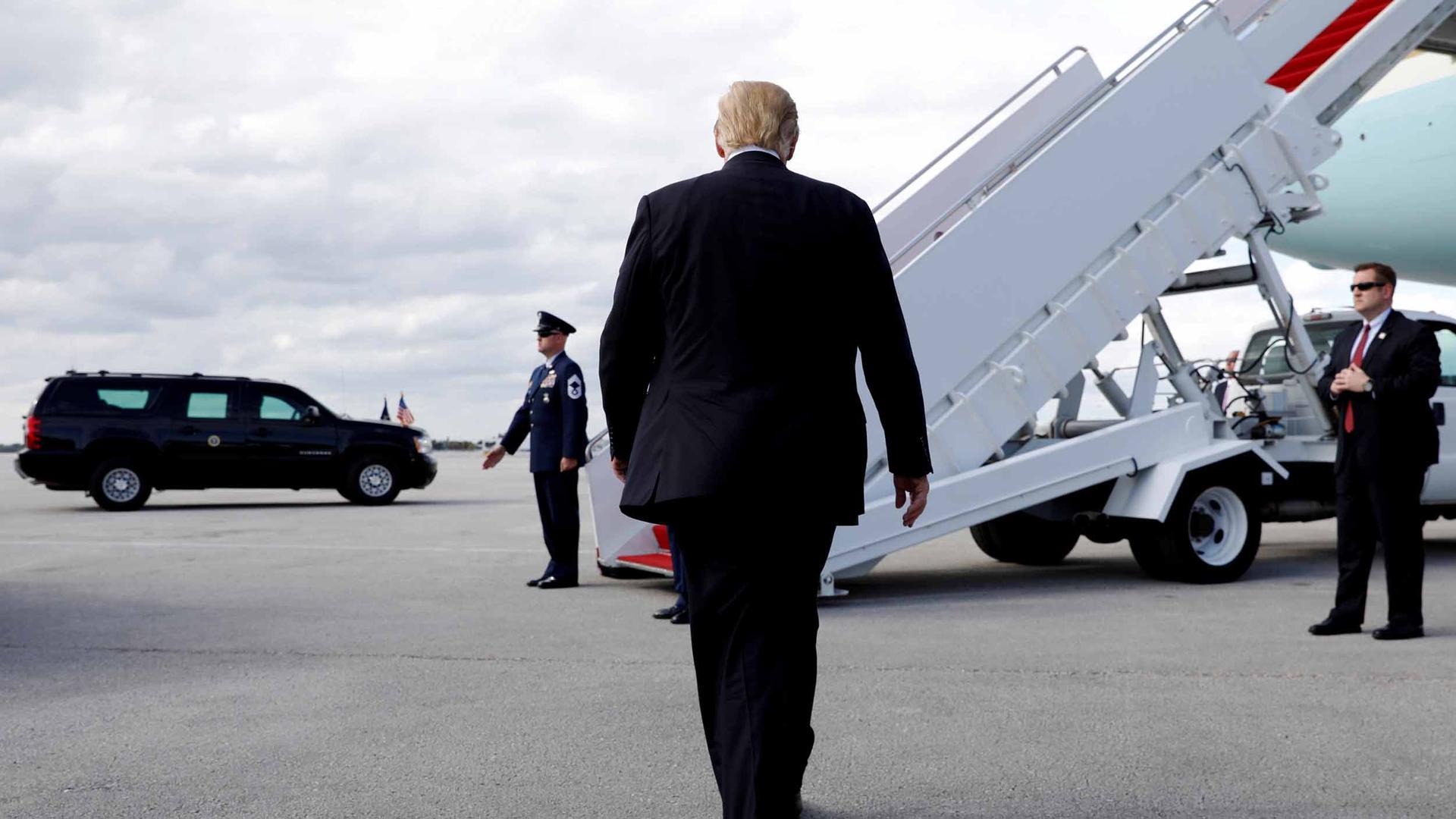 US President Donald Trump walks toward steps leading to an airplane