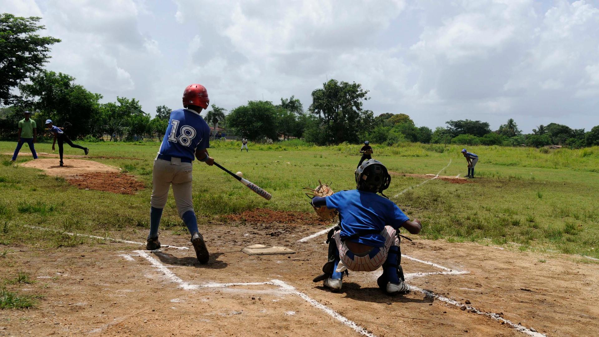 A boy swings from home base. 