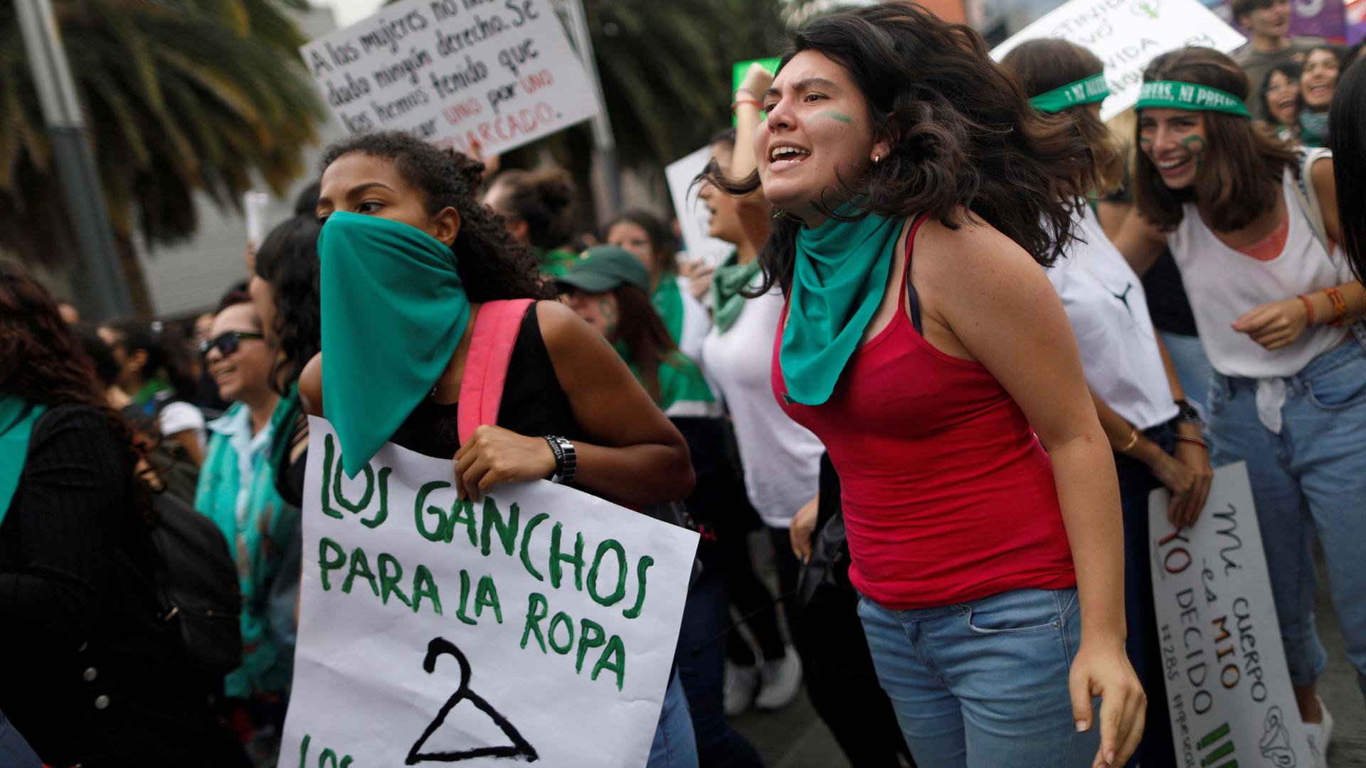 Women with green bandanas protest in a crowd