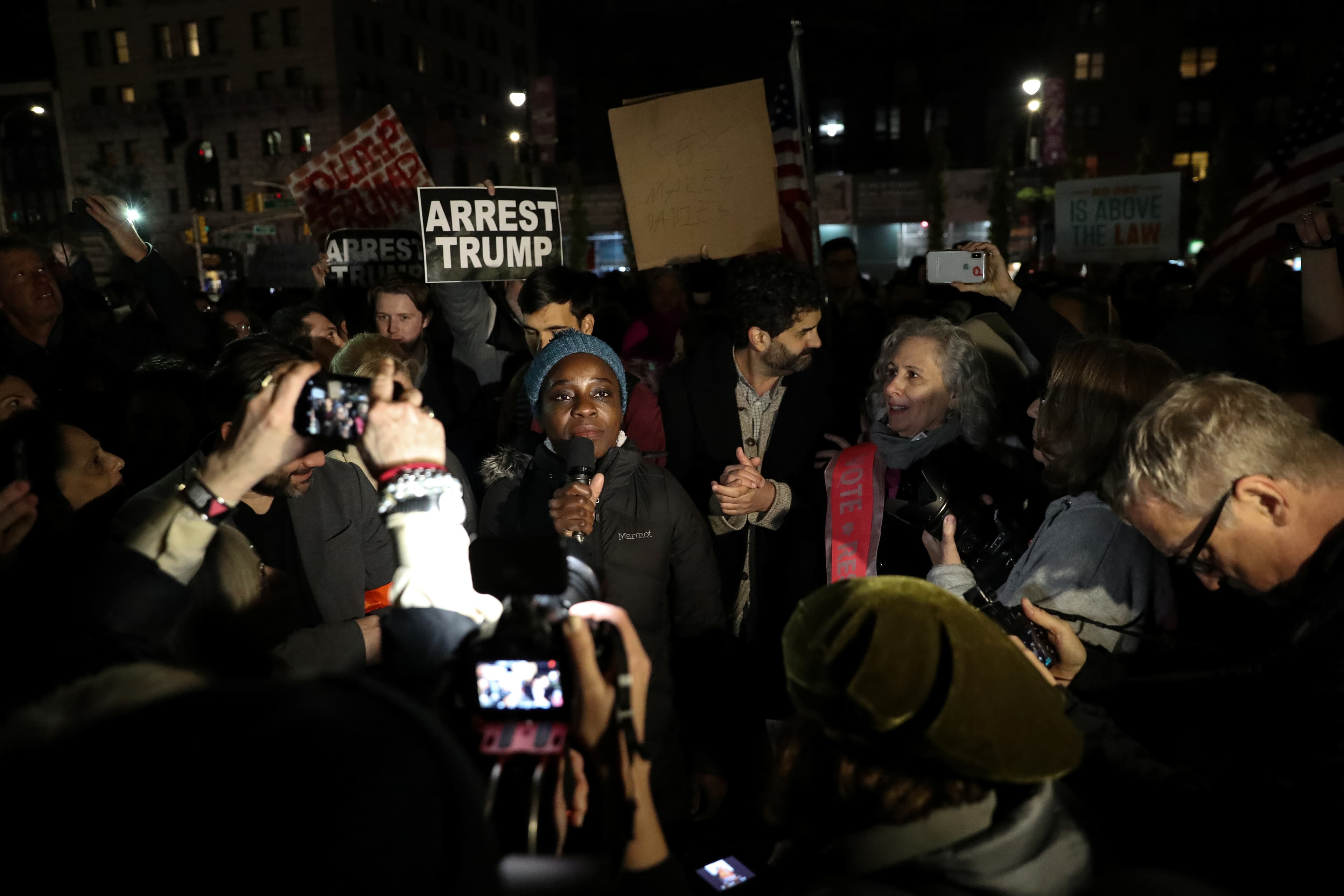 A woman speaks to a crowd gathered around her.