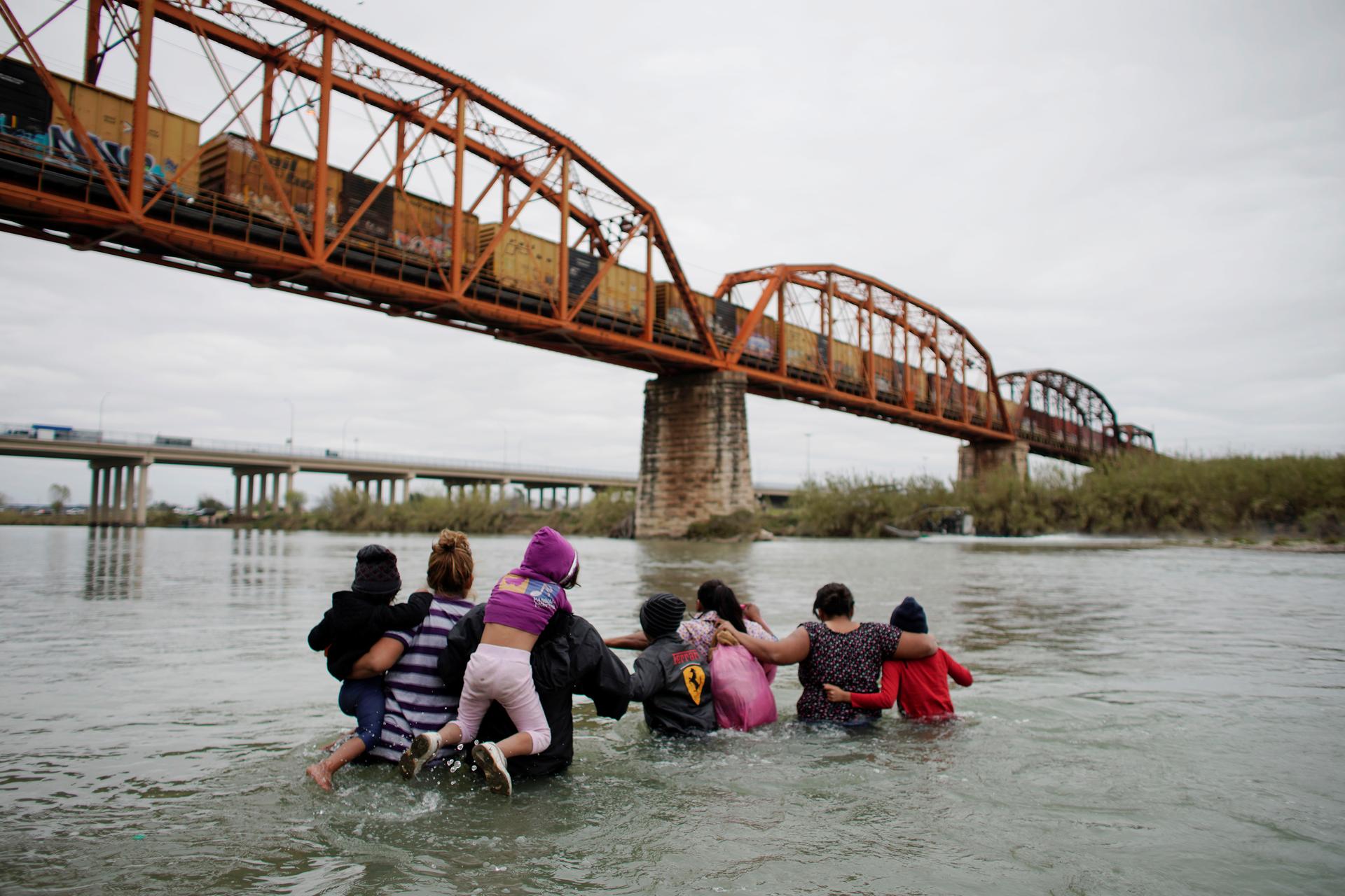 Migrants try to cross a river.