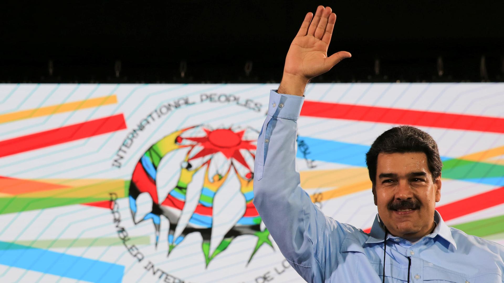 Maduro waves in front of a white flag 