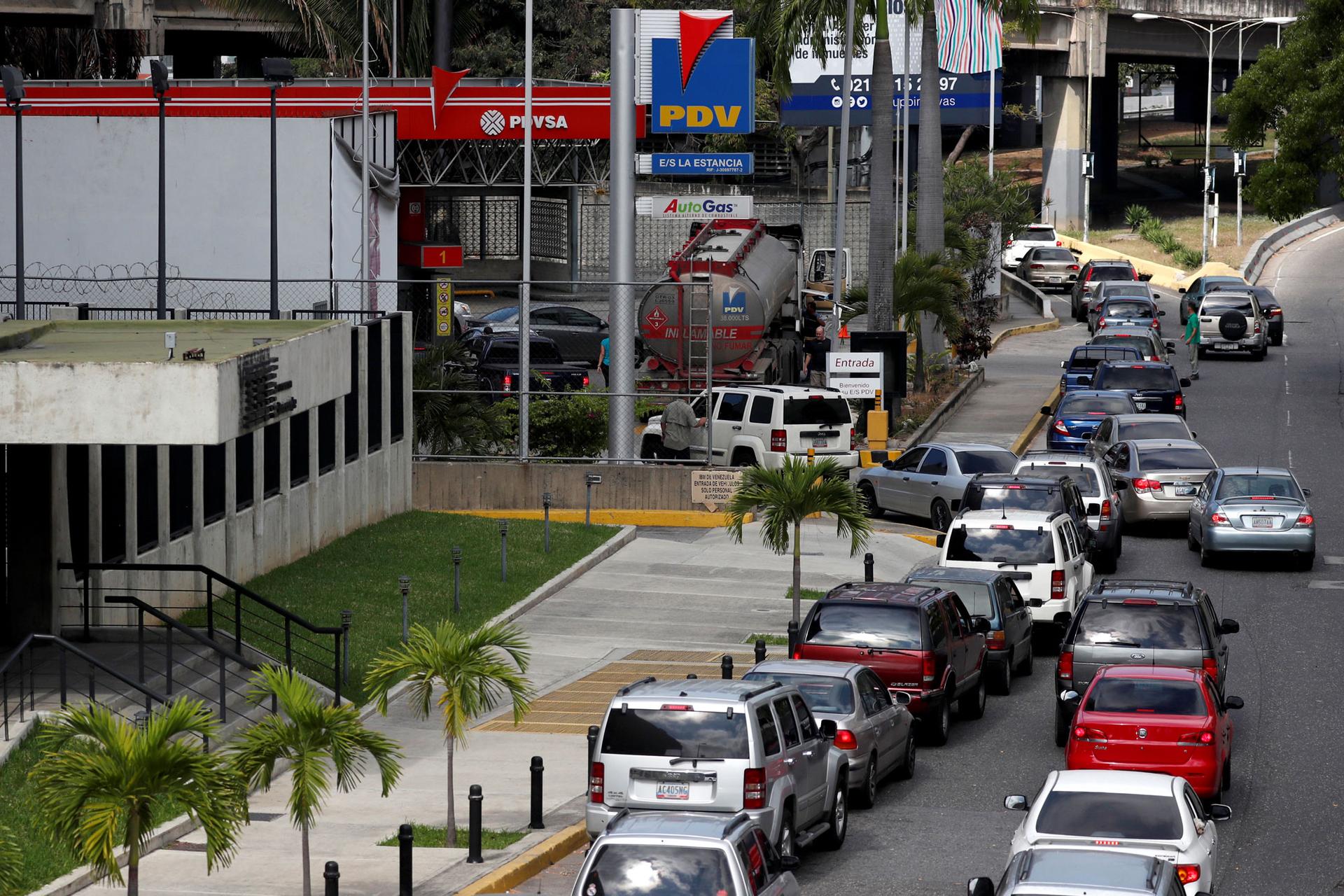 A long line of cars are shown down the street of a gas station in Caracas.