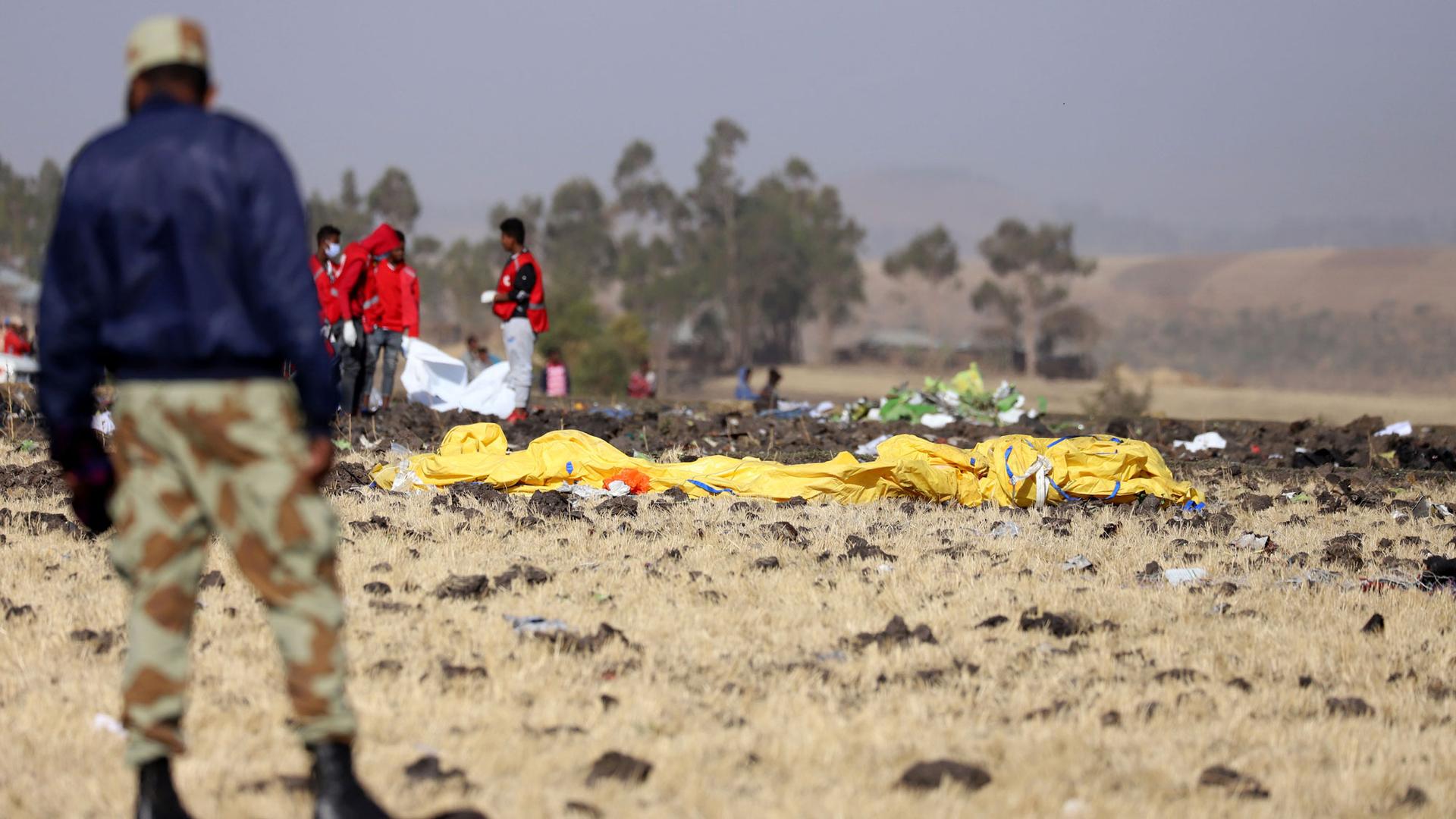 Members of the search and rescue mission are shown on the scene of the Ethiopian Airlines Flight ET 302 plane crash with a large yellow object in the middle of the photo.