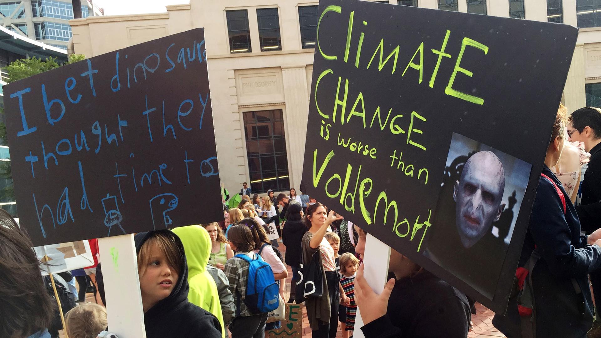 Protesters are shown with placards that read, "Climate change is worse then Voldemort."