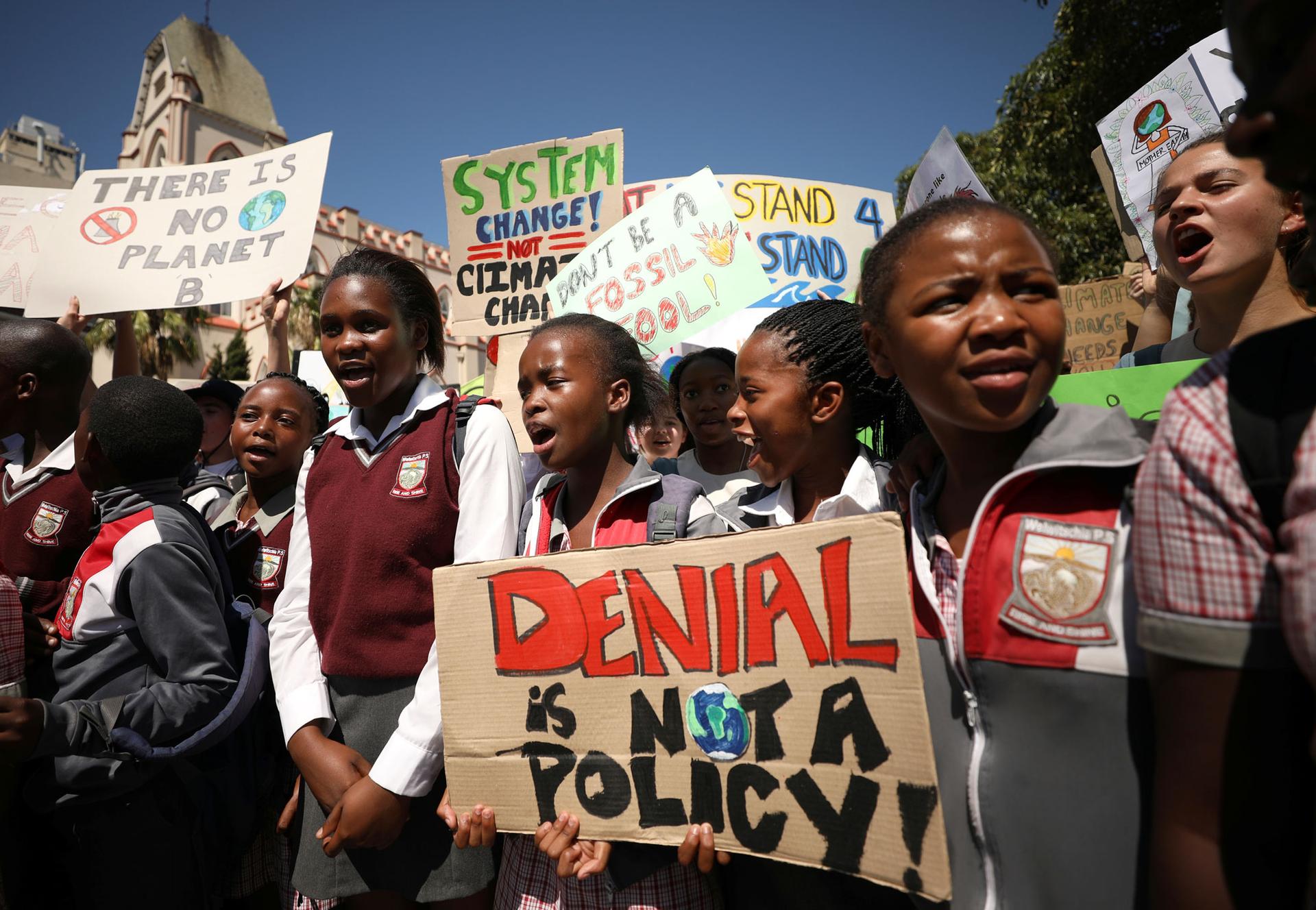 Students are shown protesting wearing their school uniforms and carrying a sign that reads: 