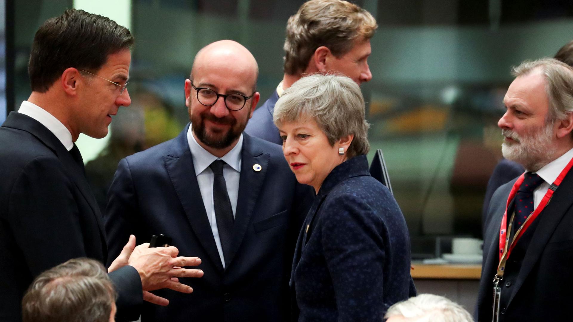 Britain's Prime Minister Theresa May is shown in the middle of a group of three men, all wearing dark suits.