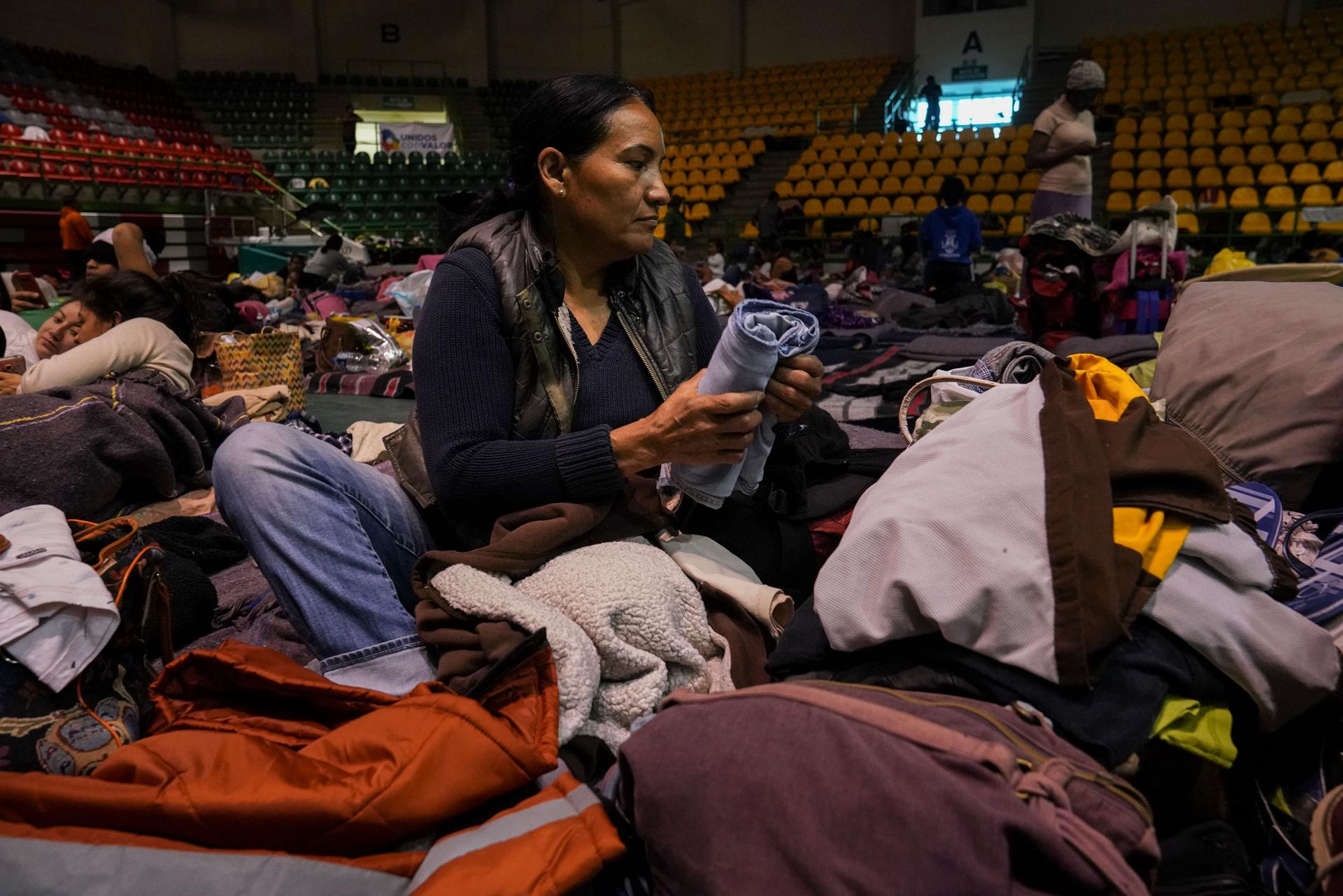Sandra García is shown sitting on mat on the floor of a gymnasium and folding clothes.