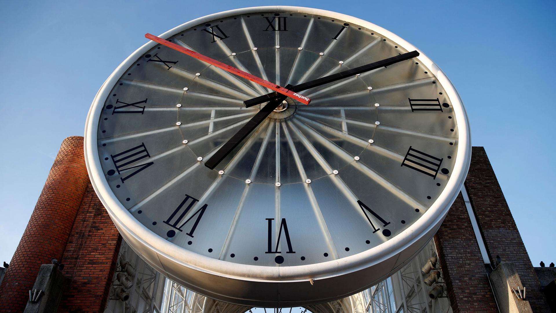 The large clock face over the entrance of Cergy-Saint-Christophe railway station is shown with the time of 7:10.