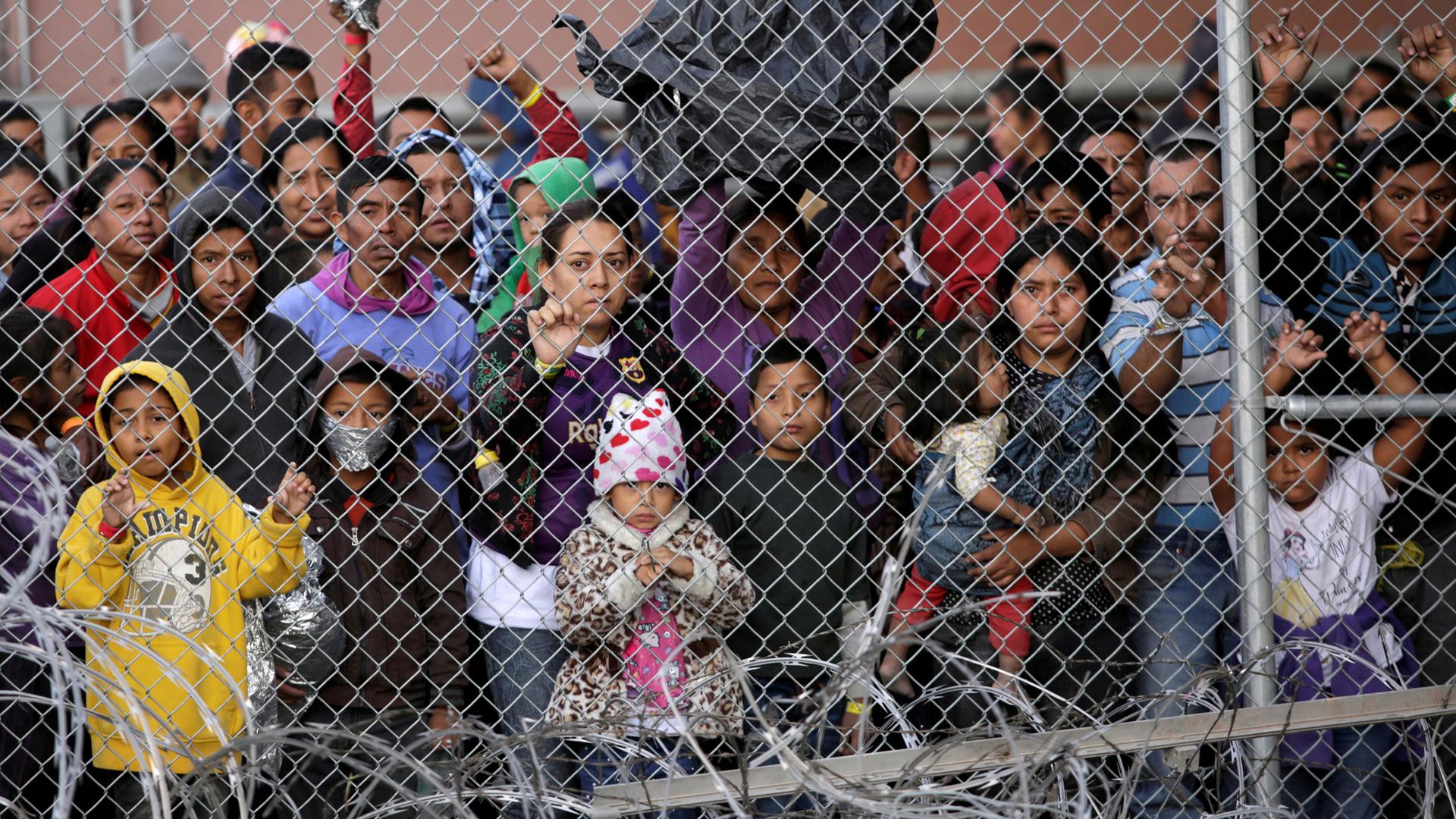 Central American migrants are seen inside an enclosure, behind a chain-link fence, where they are being held by US Customs and Border Protection.