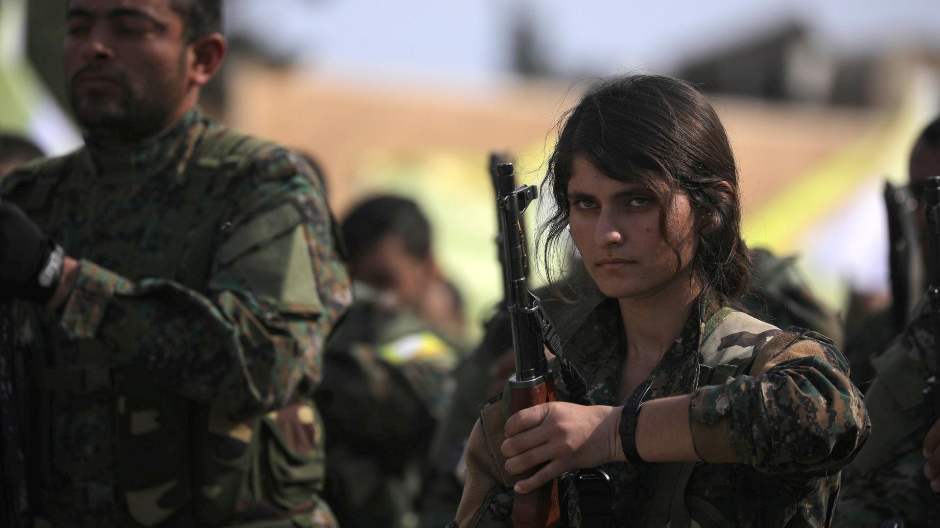 woman wearing military fatigues holds a gun