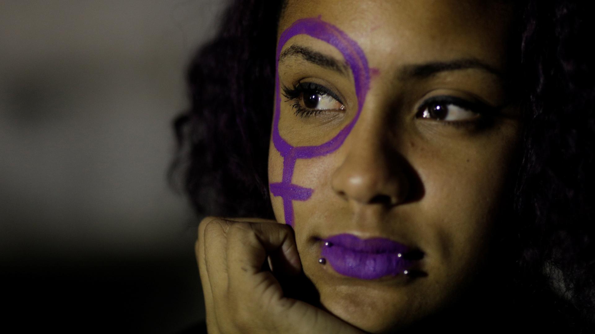 a close up of an abortion rights activist with purple paint on her face 