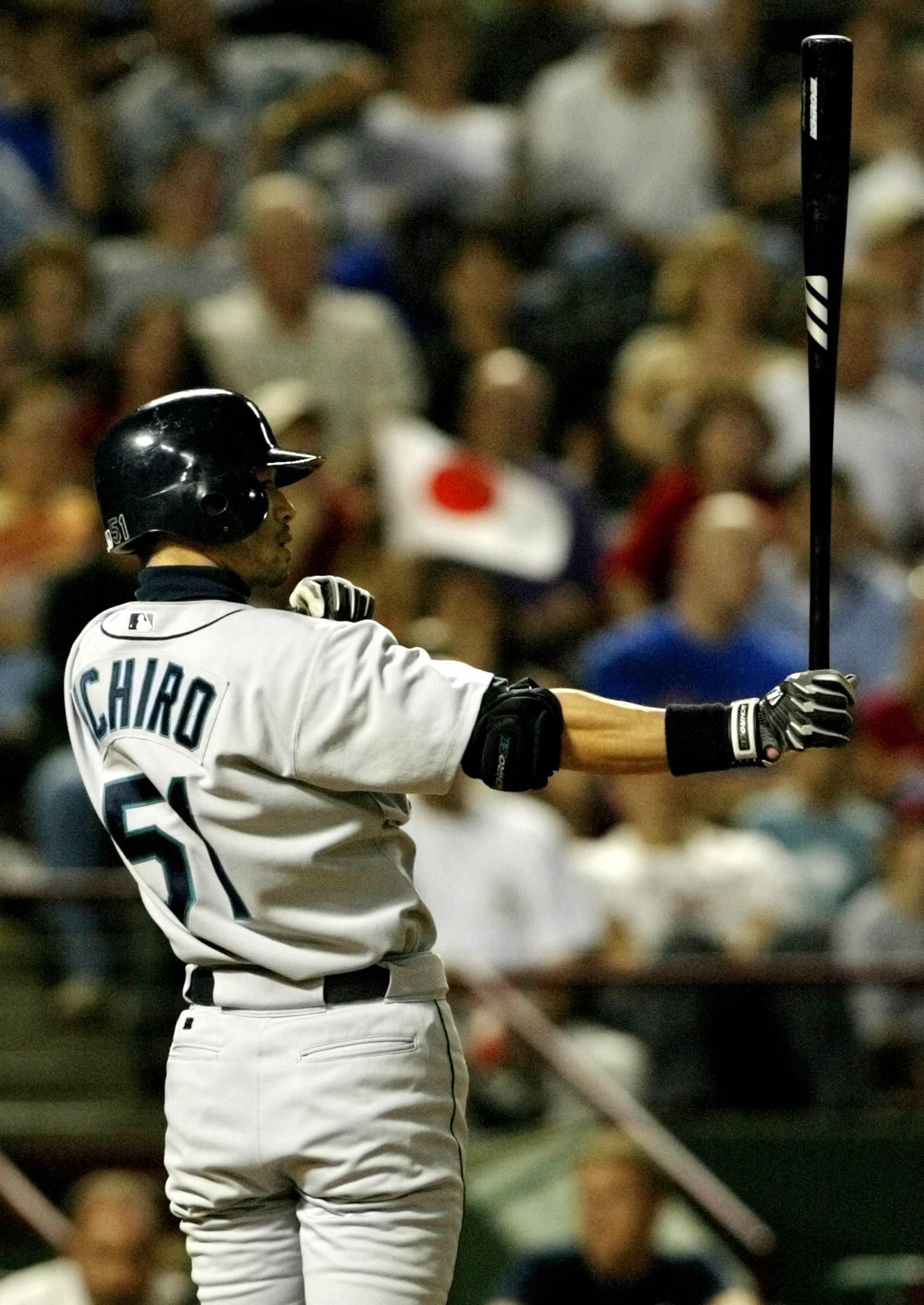 Seattle Mariners outfielder Ichiro sets up in the batter's box as a fan waves a Japanese flag in the background at a game against the Texas Rangers in Arlington, Texas, September 24, 2004. Ichiro would break the record for most hits in a single season tha