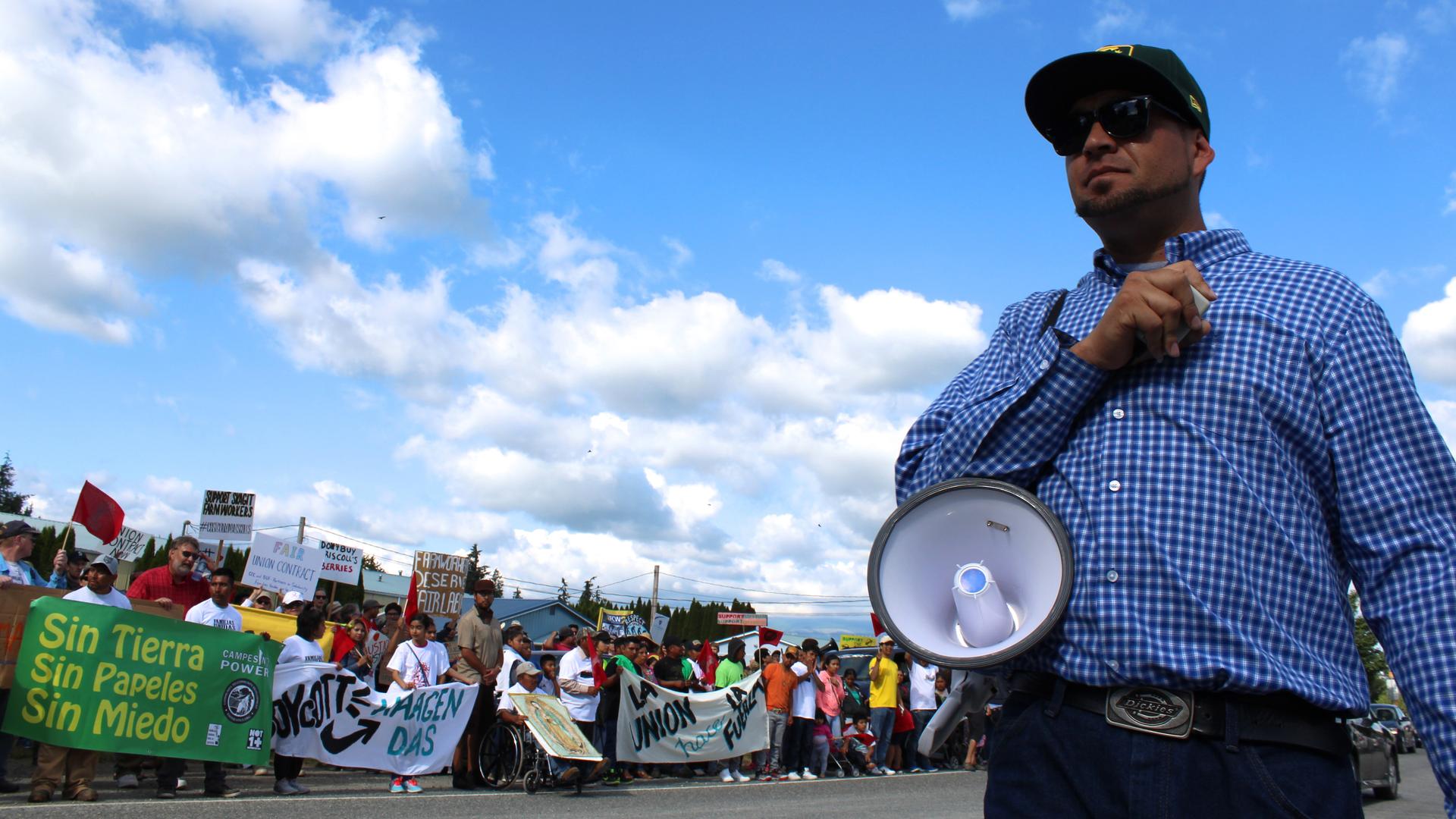 A man with a bullhorn stands in front of a line of protesters