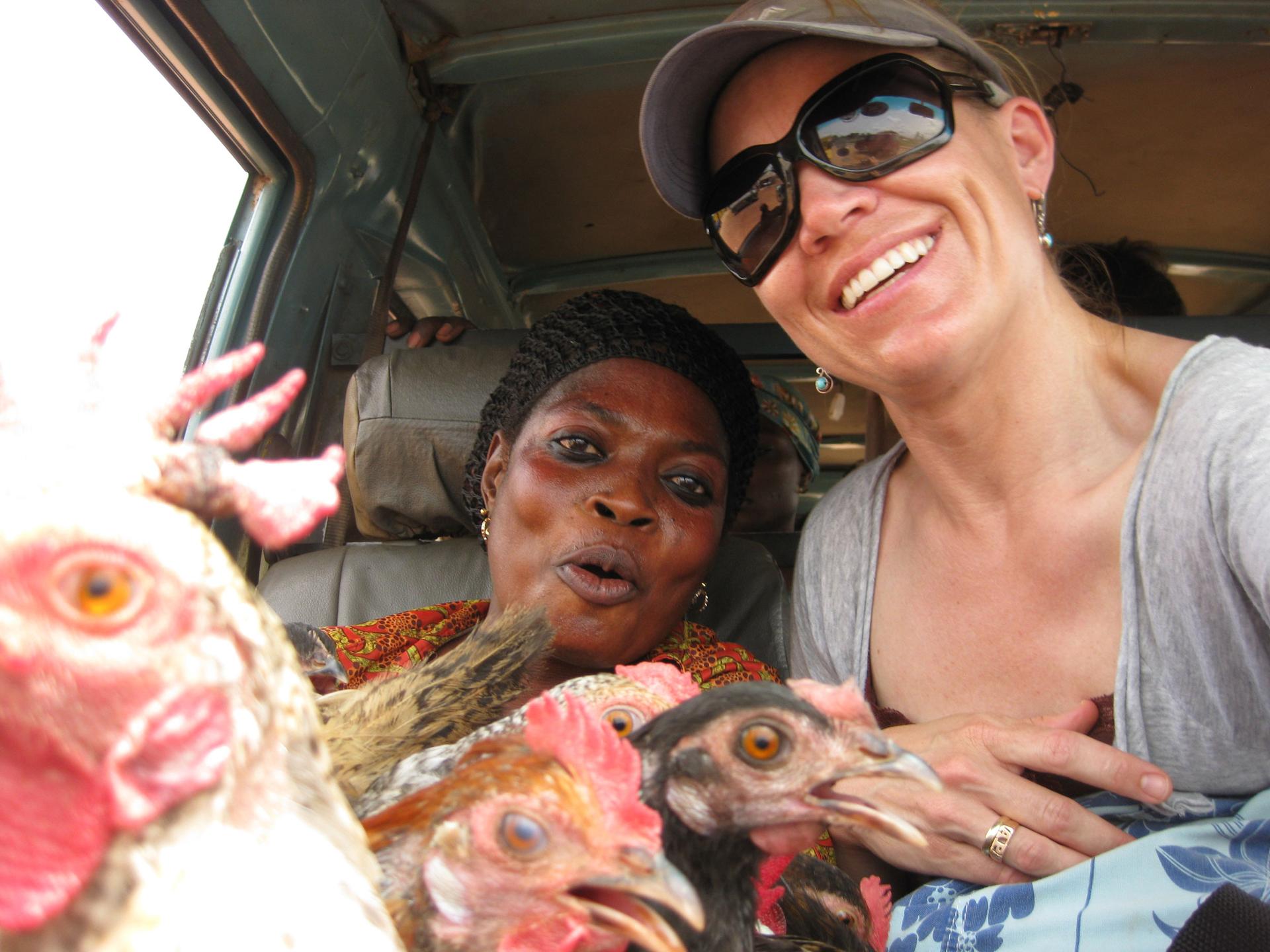 Two women pose for a photo with several chickens