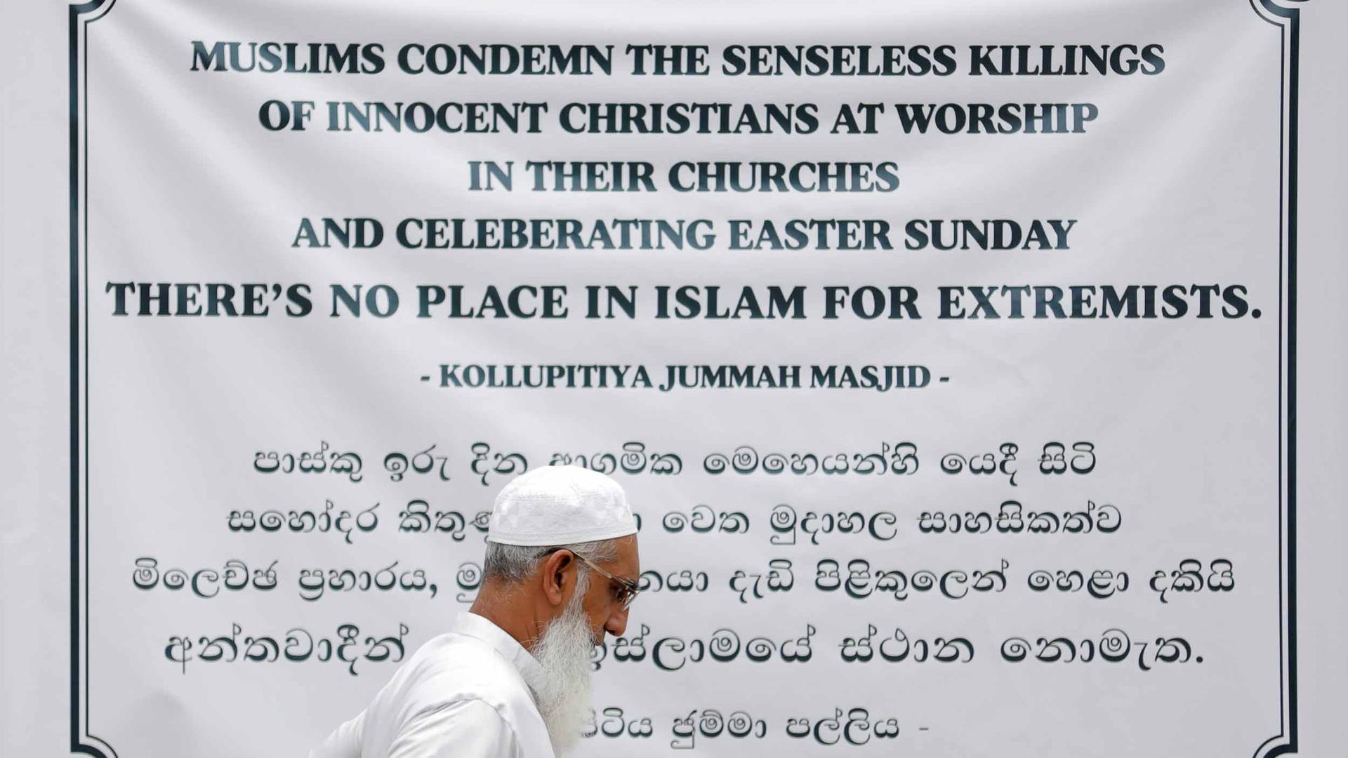 A man walks by a large banner that reads "Muslims condemn the senseless killings of innocent Christians at worship in their churches and celebrating Easter Sunday. There's no place in Islam for extremists."