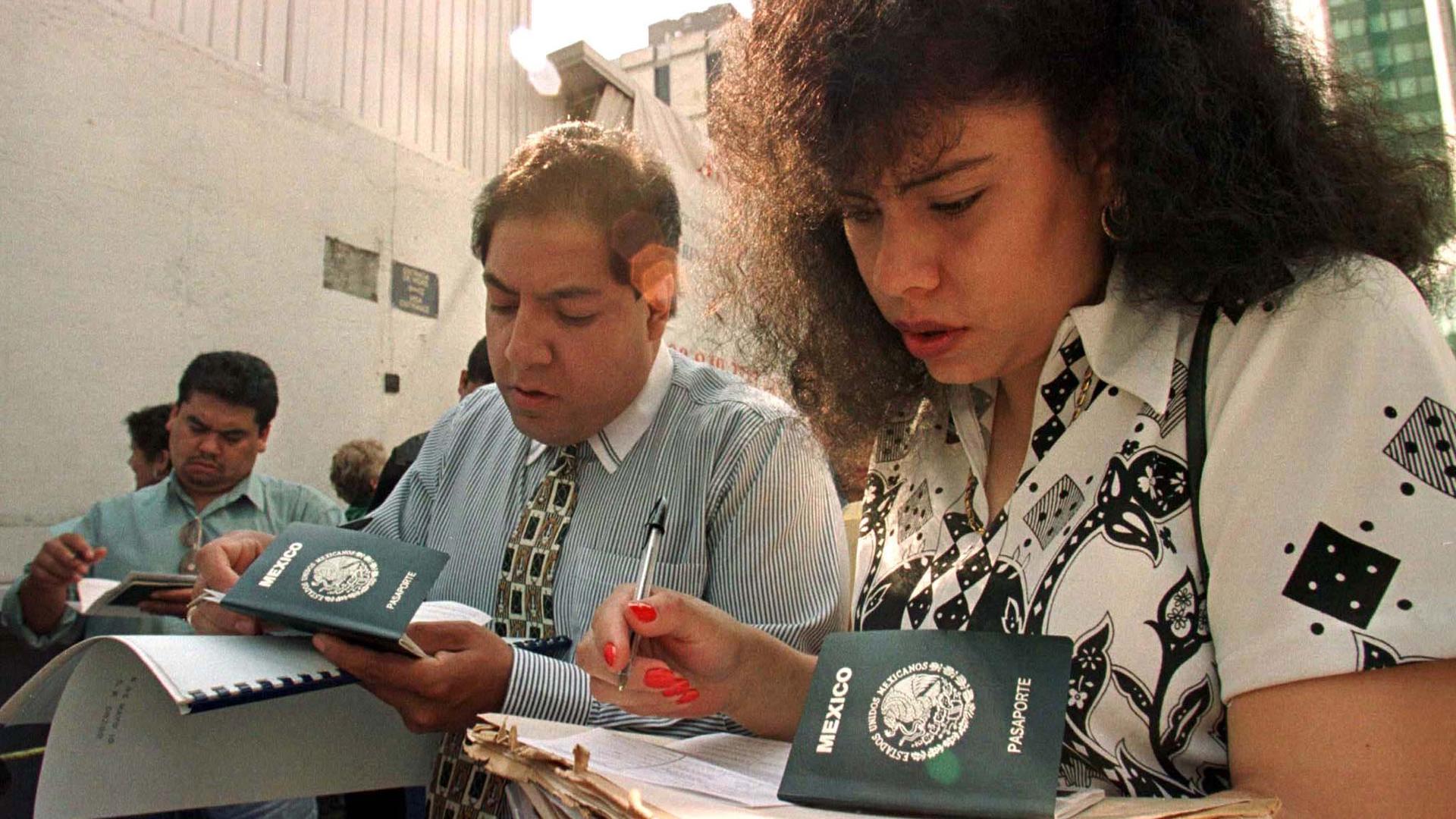 A man and a woman fill out forms with Mexican passports in the frame
