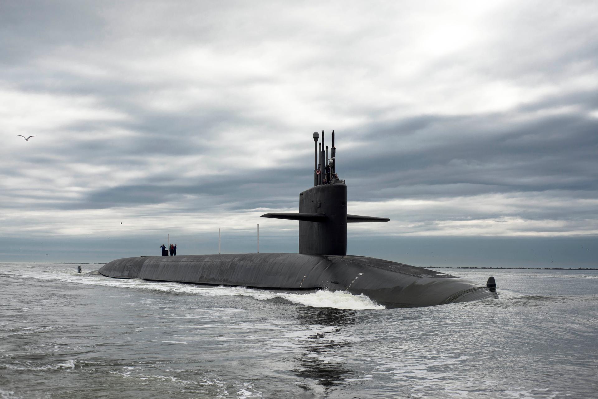 Top of grey submarine sticks out above the water.