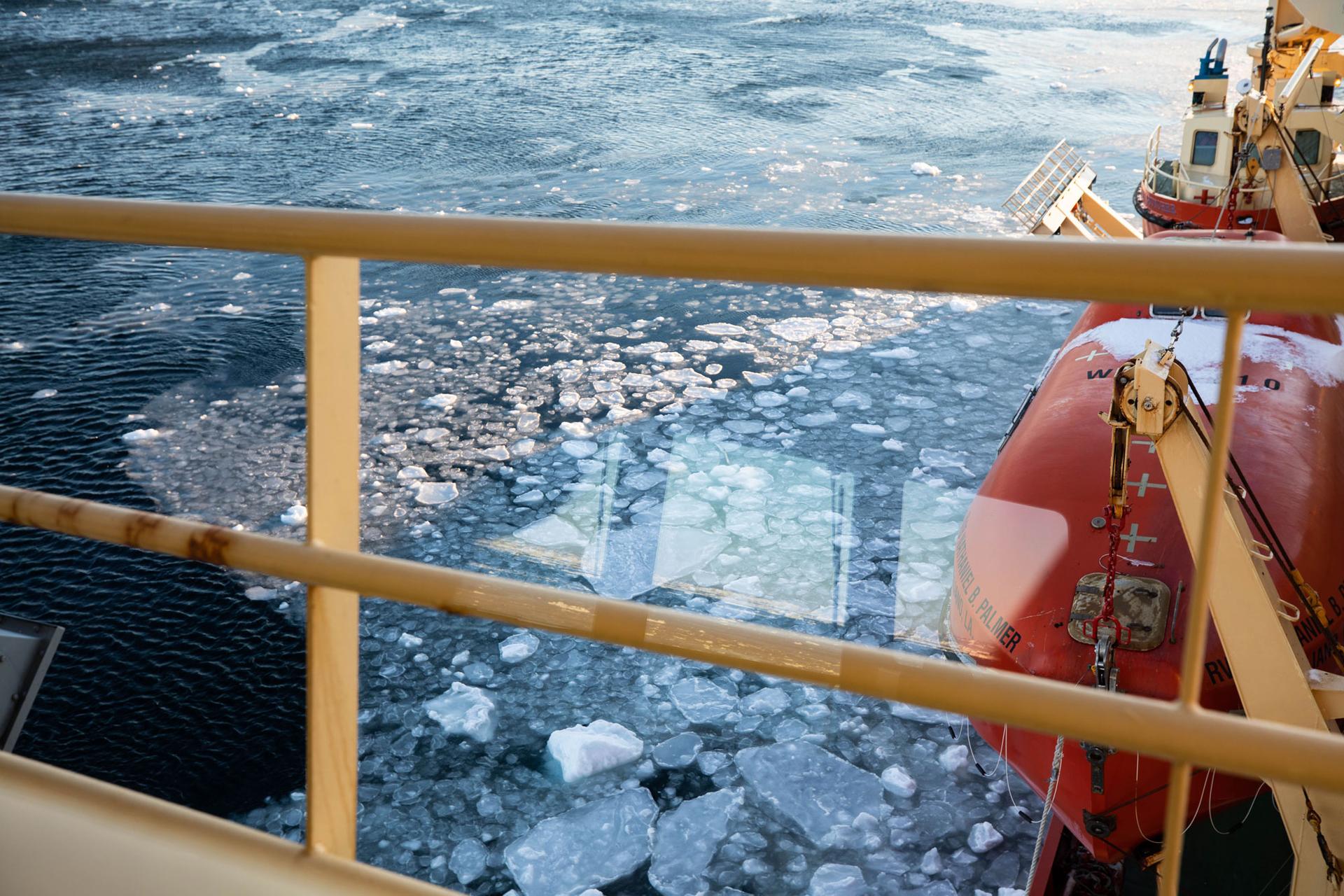 The yellow railing of the a research vessel is in the nearground with ice shown forming in the Amundsen Sea.