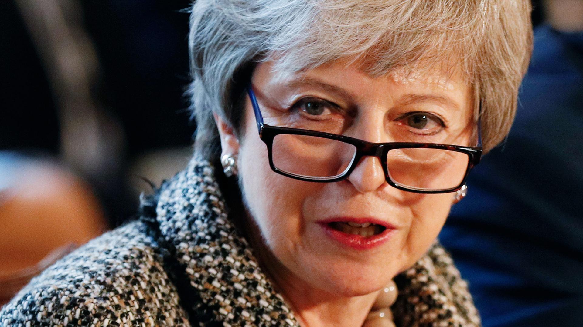 A close-up photograph of Britain's Prime Minister Theresa May who is wearing dark-rimmed glasses.