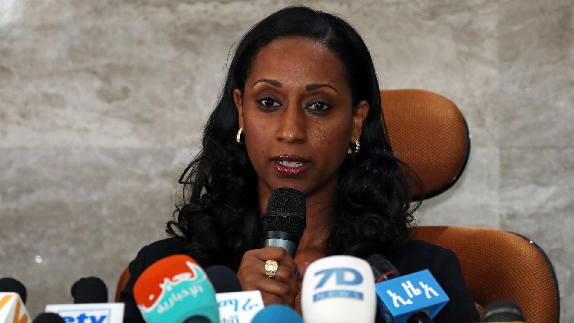 Ethiopian transport minister Dagmawit Moges is shown sitting at a chair behind several microphones.