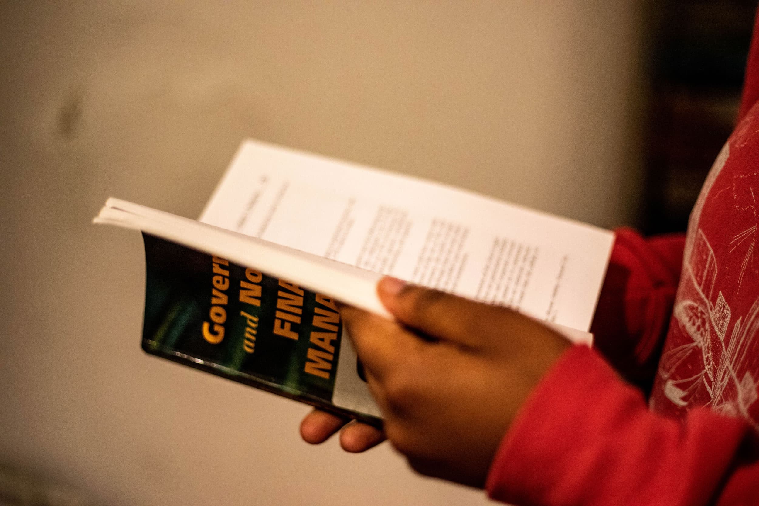 A close-up photograph of a woman holding a textbook with the word